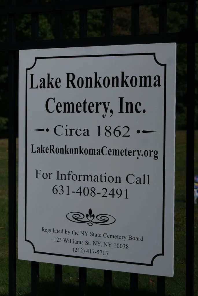 Sign for Lake Ronkonkoma Cemetery, Inc., established around 1862, with contact information and regulation details, mounted on a fence.