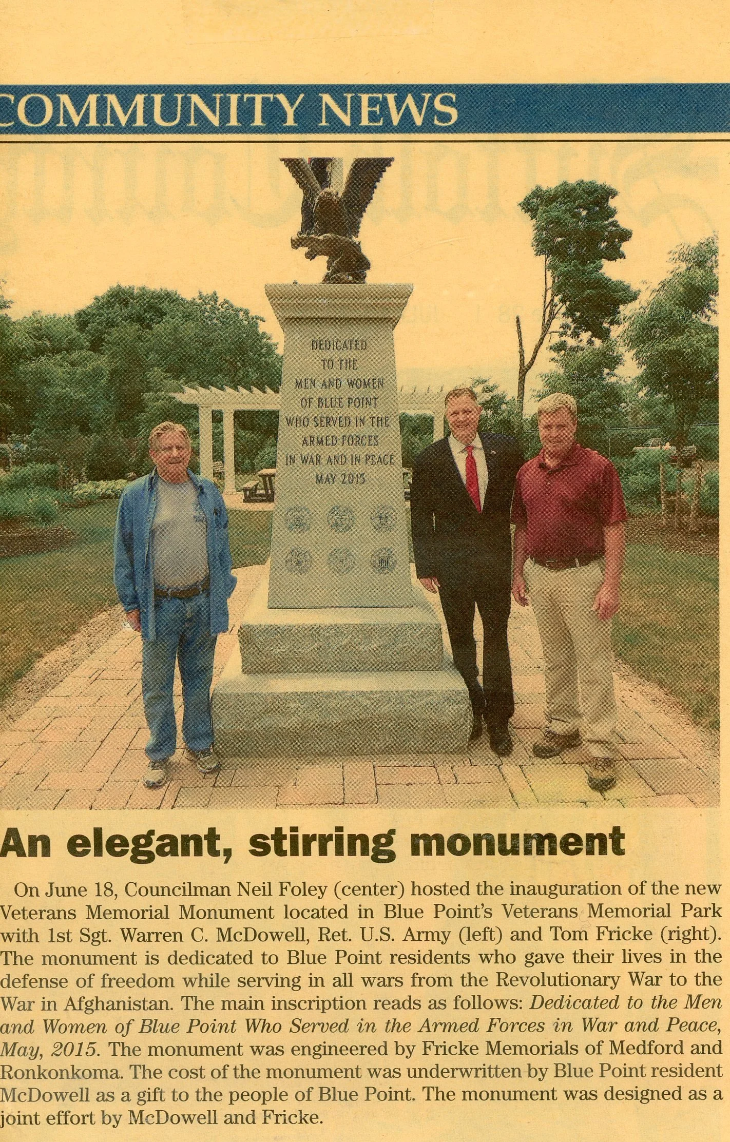 A photo of three men standing in front of a monument with an eagle on top. The monument has an inscription dedicated to the men and women of Blue Point who served in the armed forces.