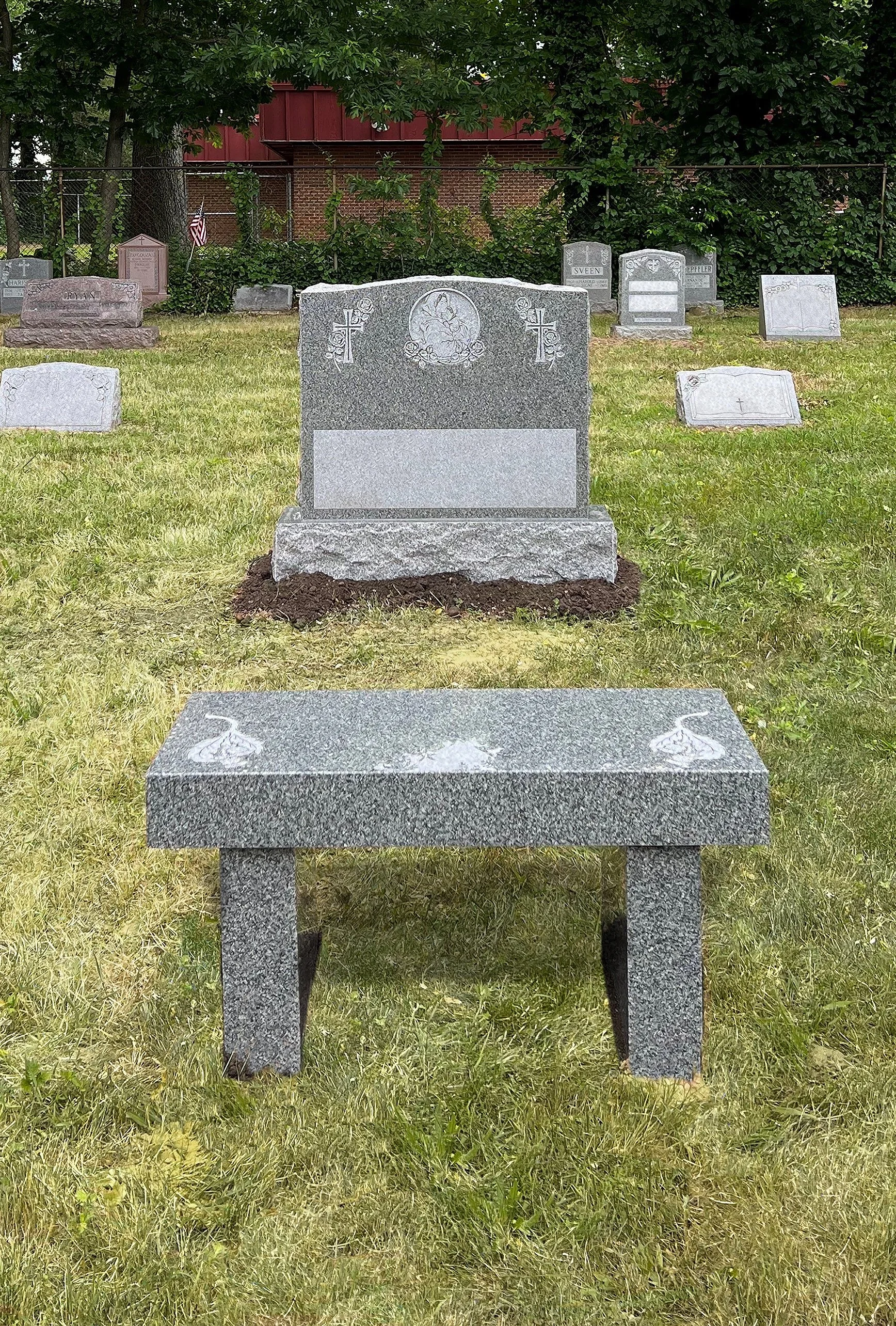 Grey bench at foot of headstone in cemetery