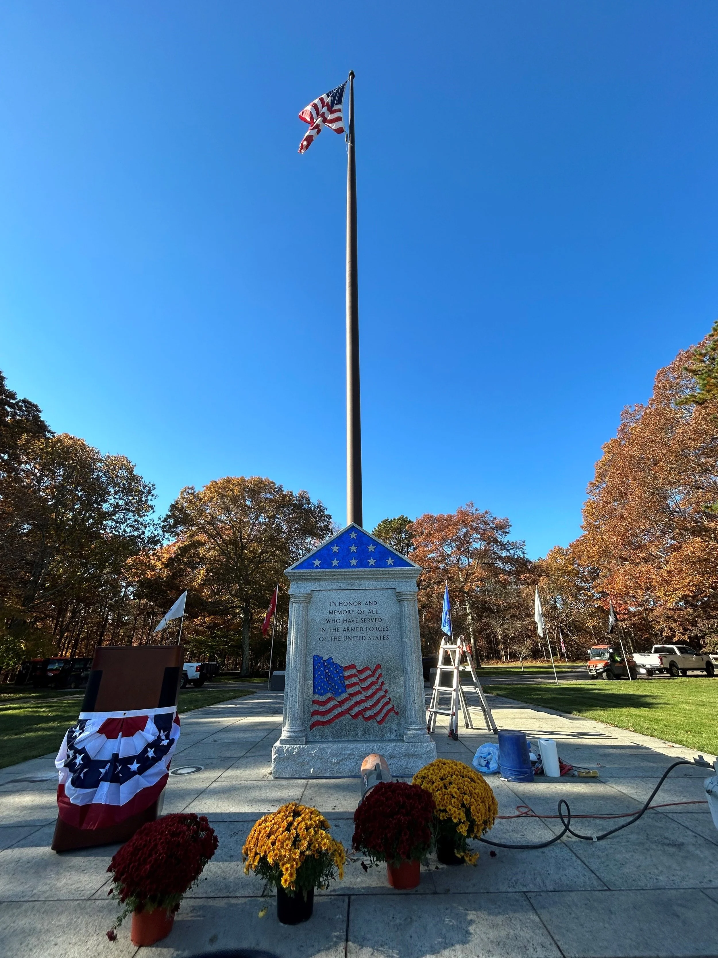 Grey granite memorial with american flag in color and flag pole behind it