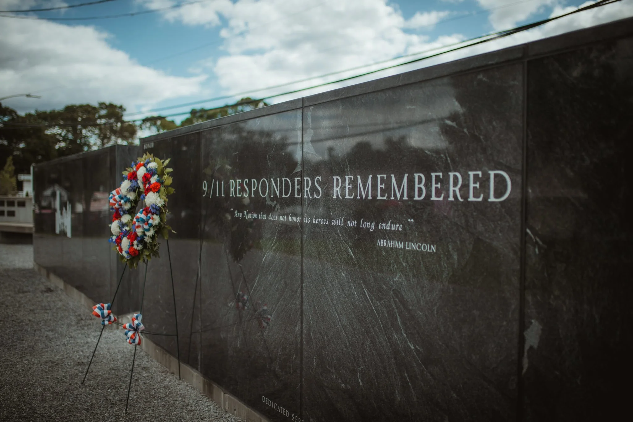 Memorial wall for 9/11 responders with a wreath of flowers and a quote by Abraham Lincoln.