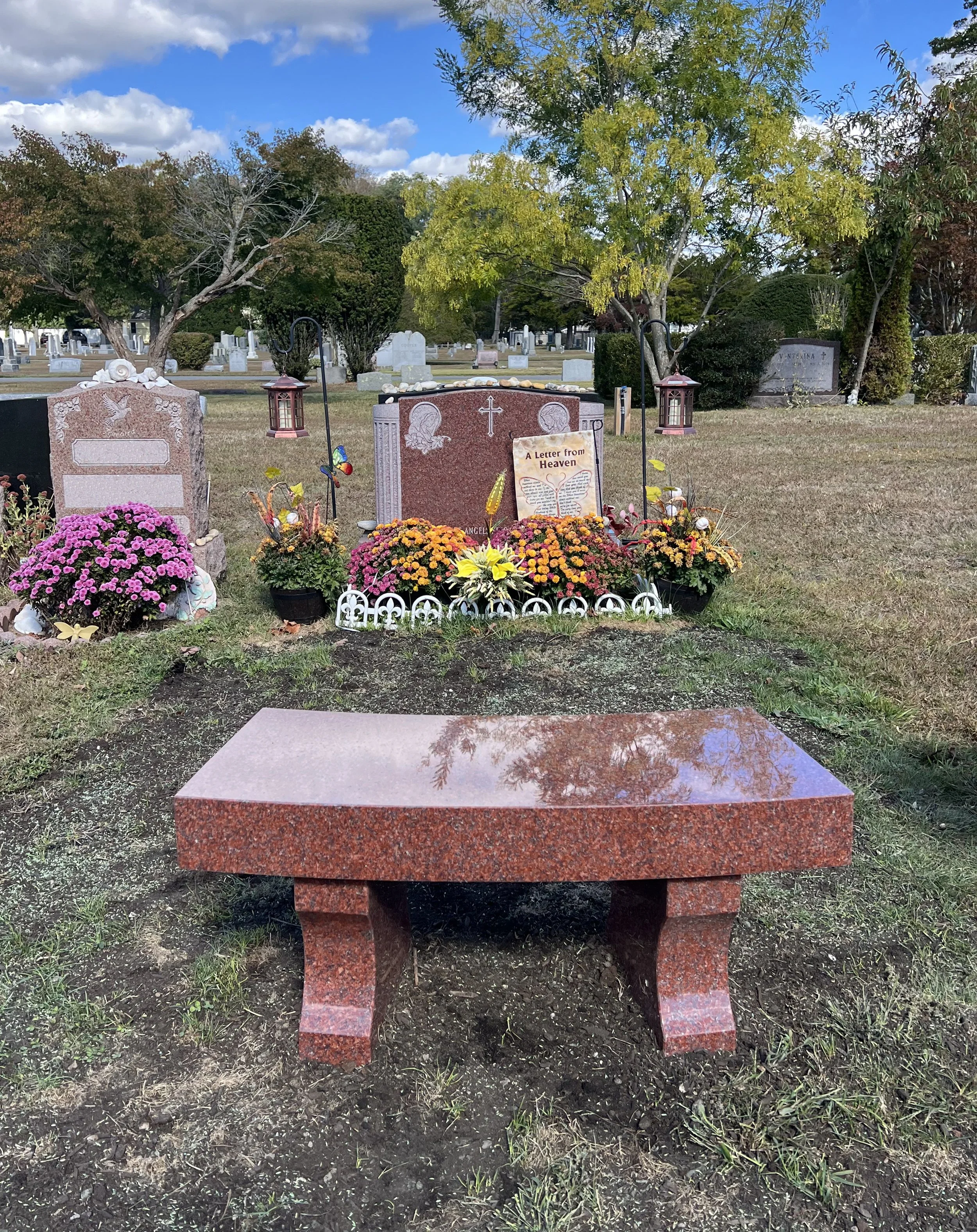 Red bench at foot of headstone in cemetery