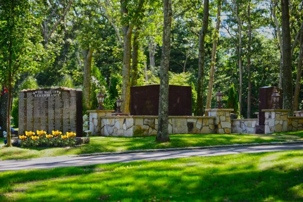 large monument titled The Wall of Remembrance with yellow flowers in the foreground