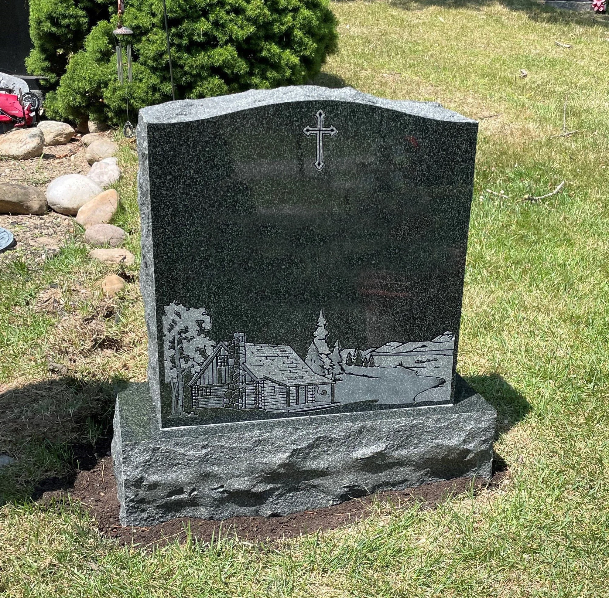 New evergreen monument with sandblast design of cabin in the woods