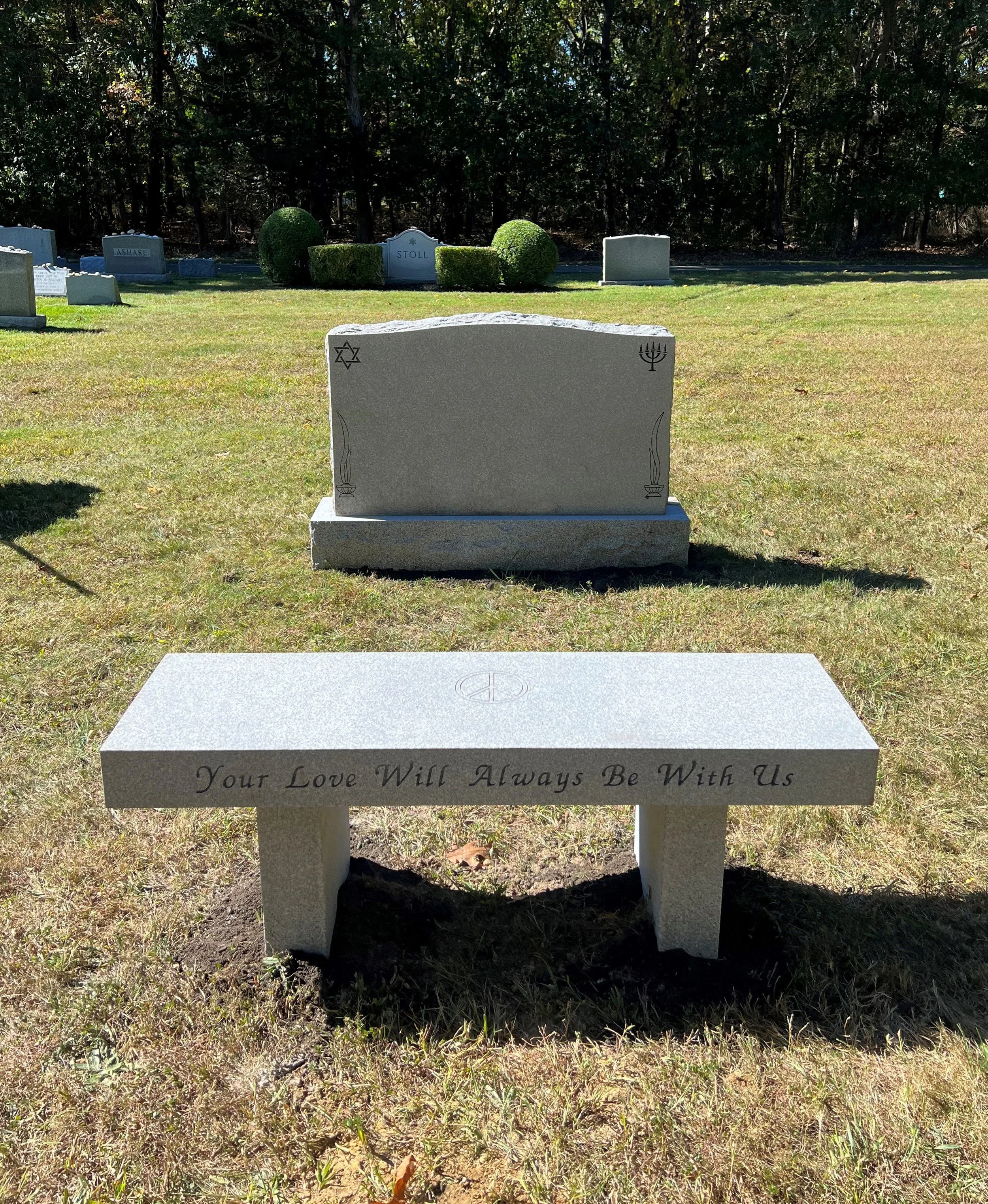 Grey bench at foot of headstone in cemetery