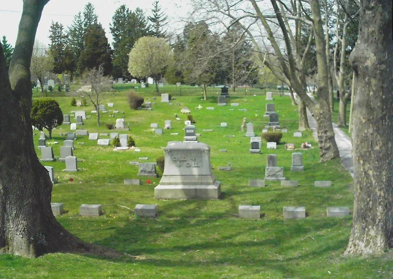View of cemetery with many headstones, largely grey in color.