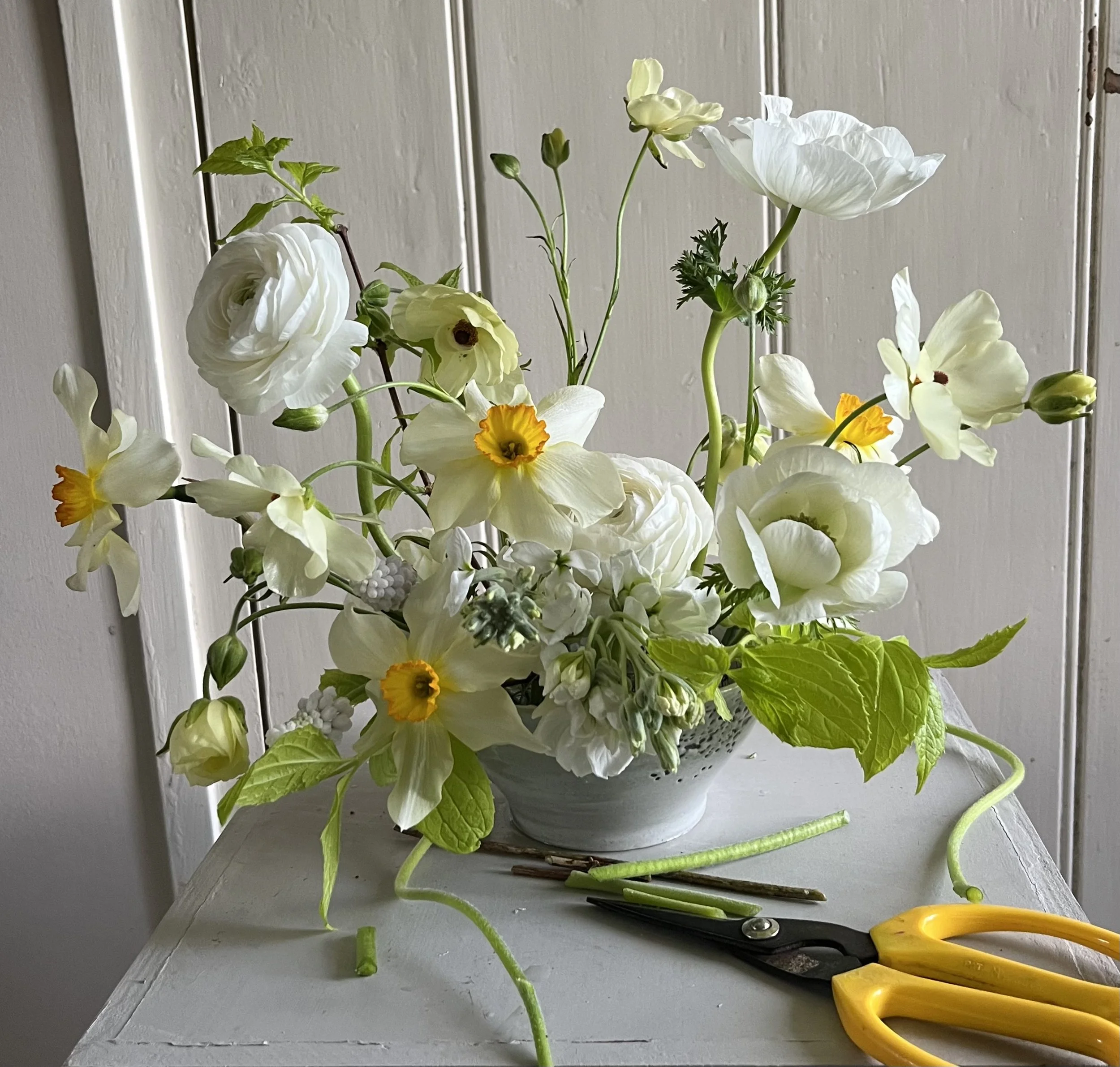 Loose spring arrangement wit narcissi and ranunculus in a bowl, natural and garden-inspired