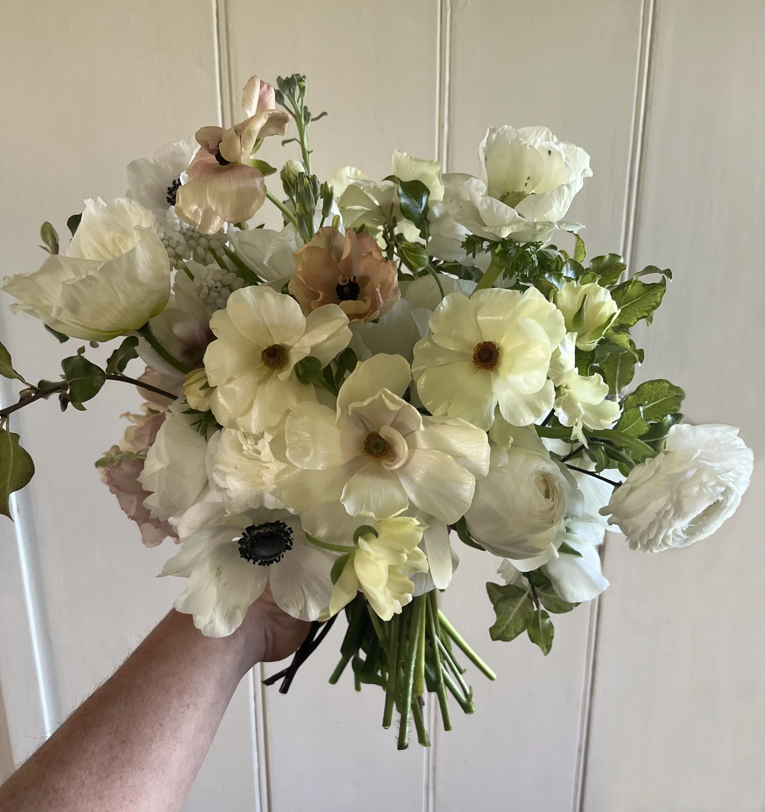 Soft spring bridal bouquet with anemones, ranunculuc and seasonal foliage