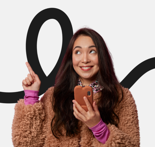 A young woman with long dark hair, wearing a fuzzy brown jacket and purple sleeves, smiling and holding a phone while pointing to a large black number zero on a white background.