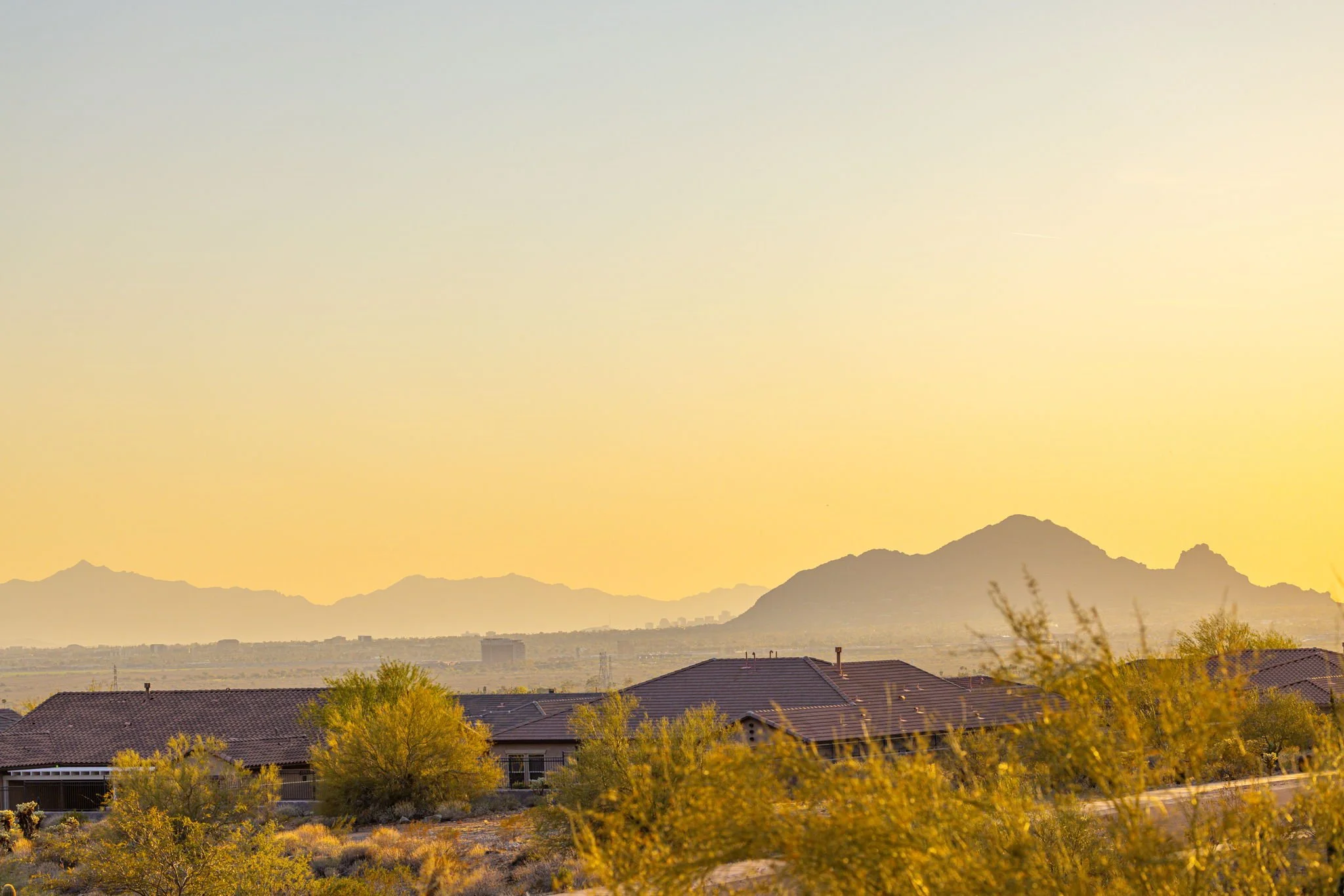 Houses in a desert landscape with mountains in the background during sunset.