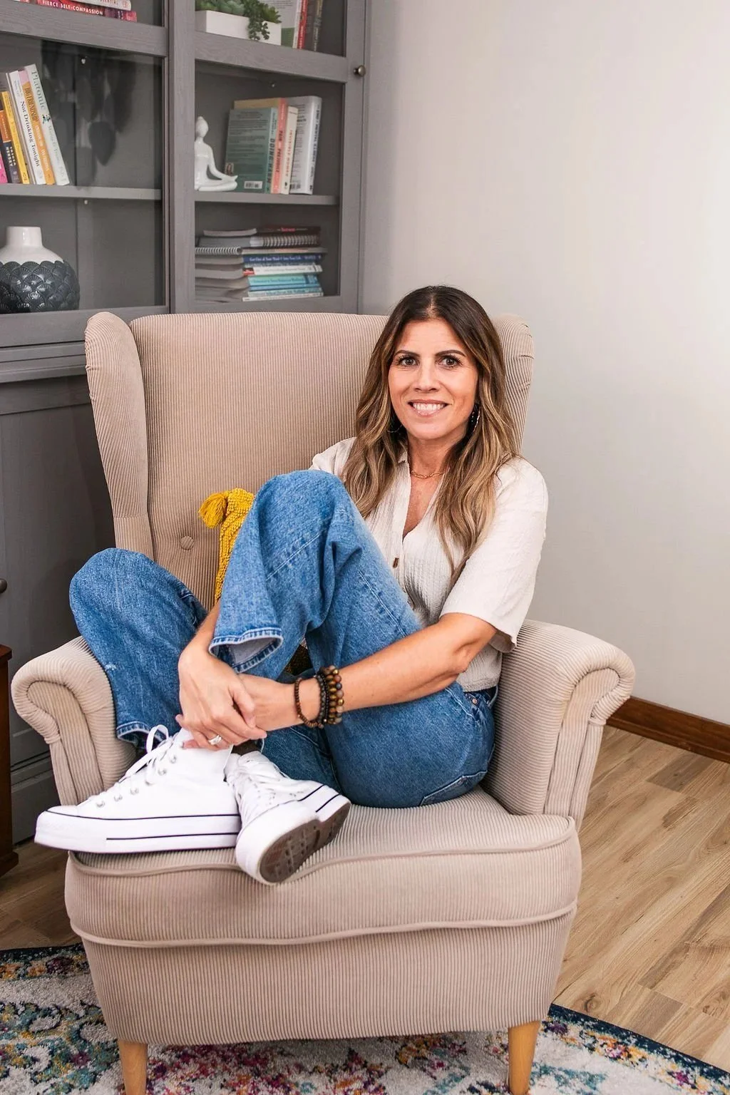Angela Langer, therapist and ADHD coach for women, smiling in an armchair in her office