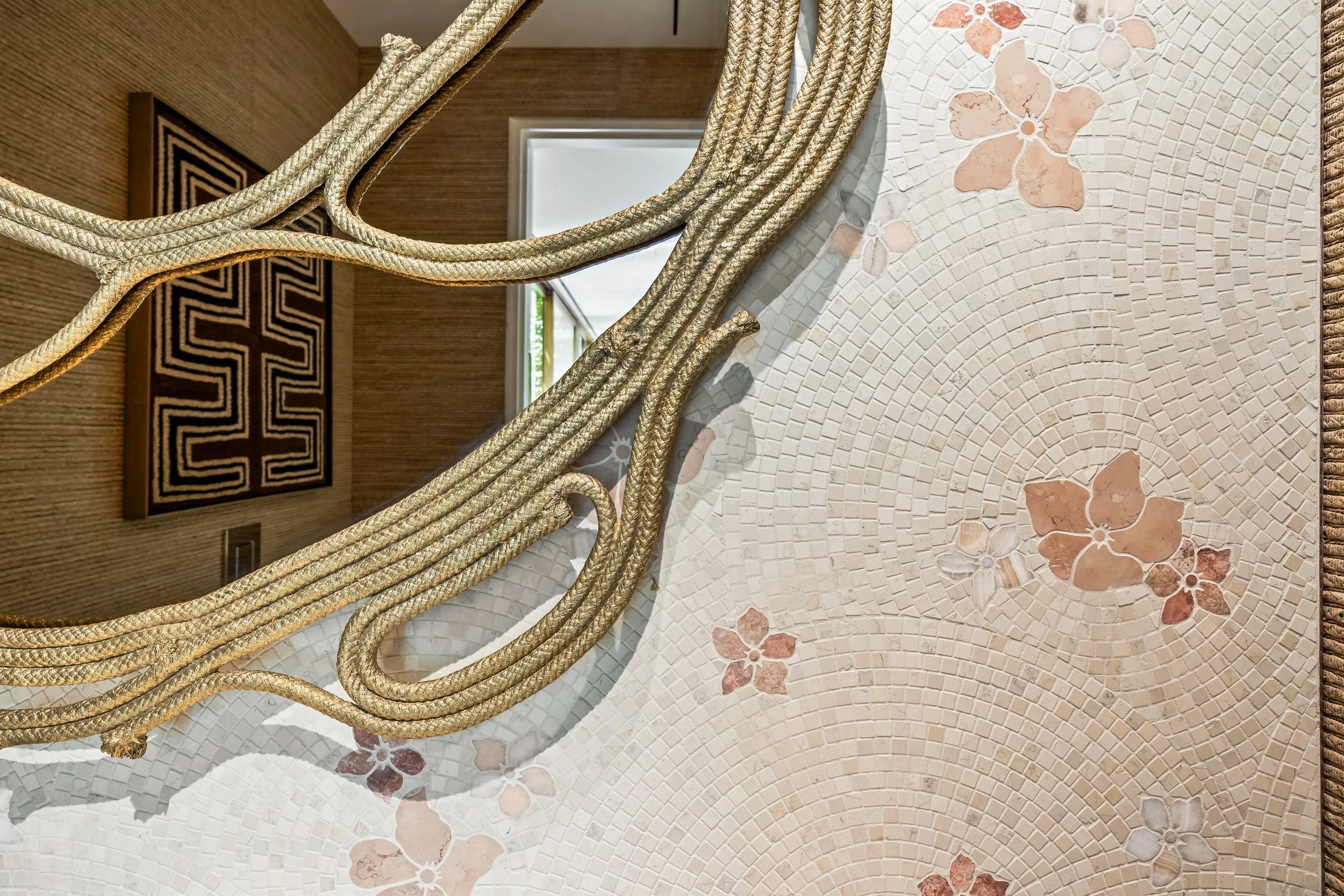 Detail of custom stone mosaic inlay featuring delicate blush floral motifs seamlessly set into a light tile backsplash.