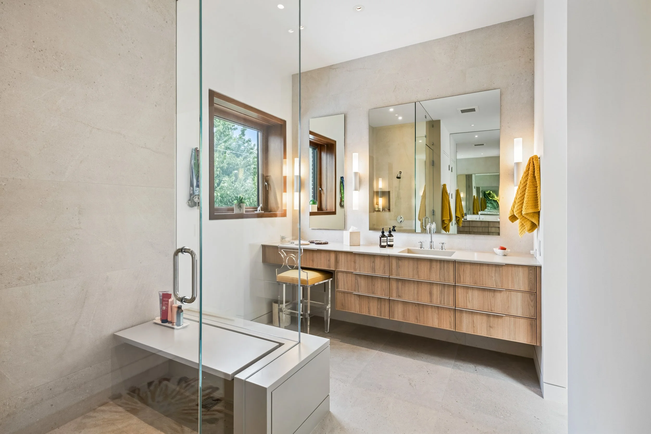 Architectural primary bathroom design with custom wood double vanity and glass walk-in shower in Lincoln Park Chicago residence.