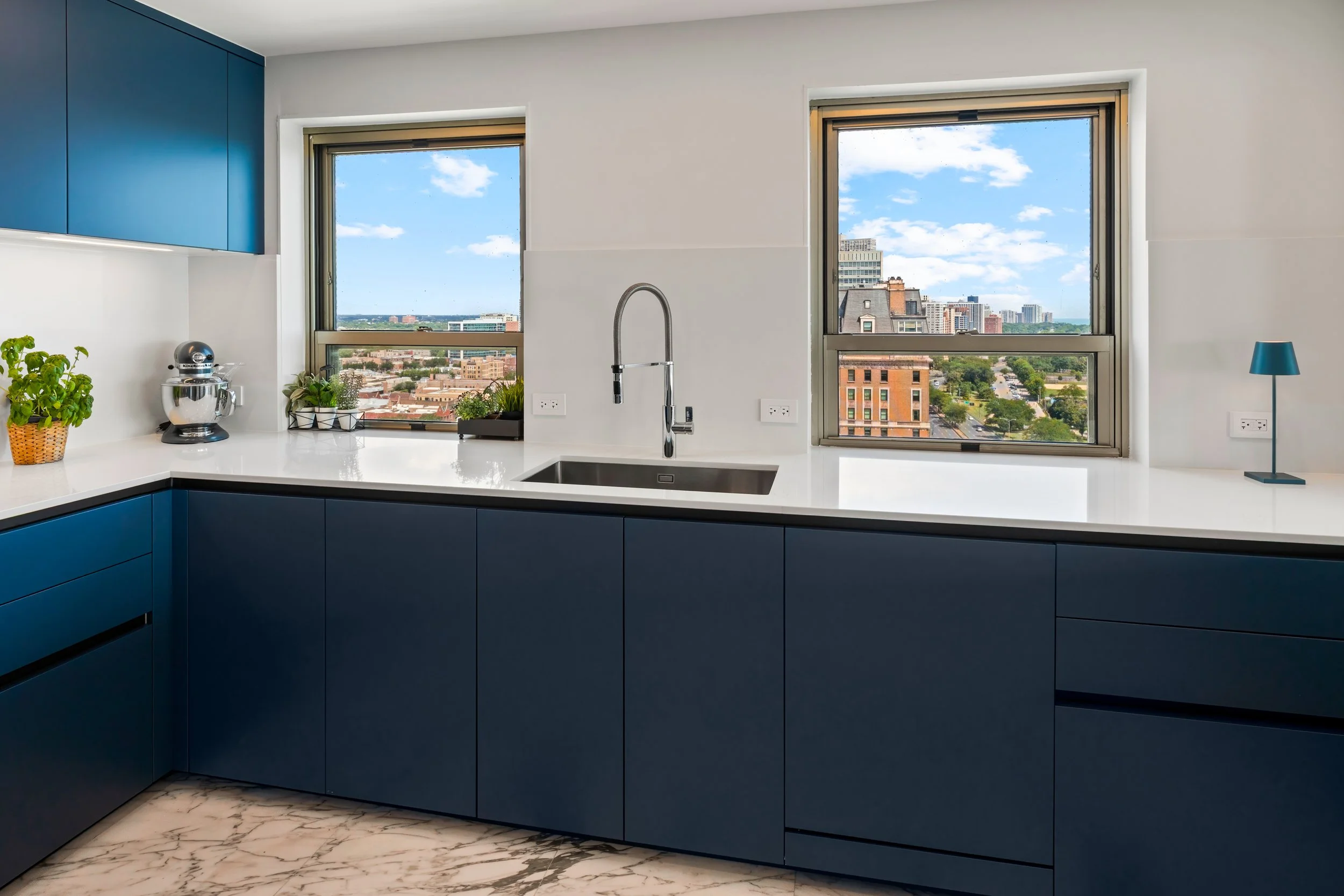 Custom cobalt blue kitchen renovation with bright window layout and quartz countertops in Lincoln Park Chicago home.