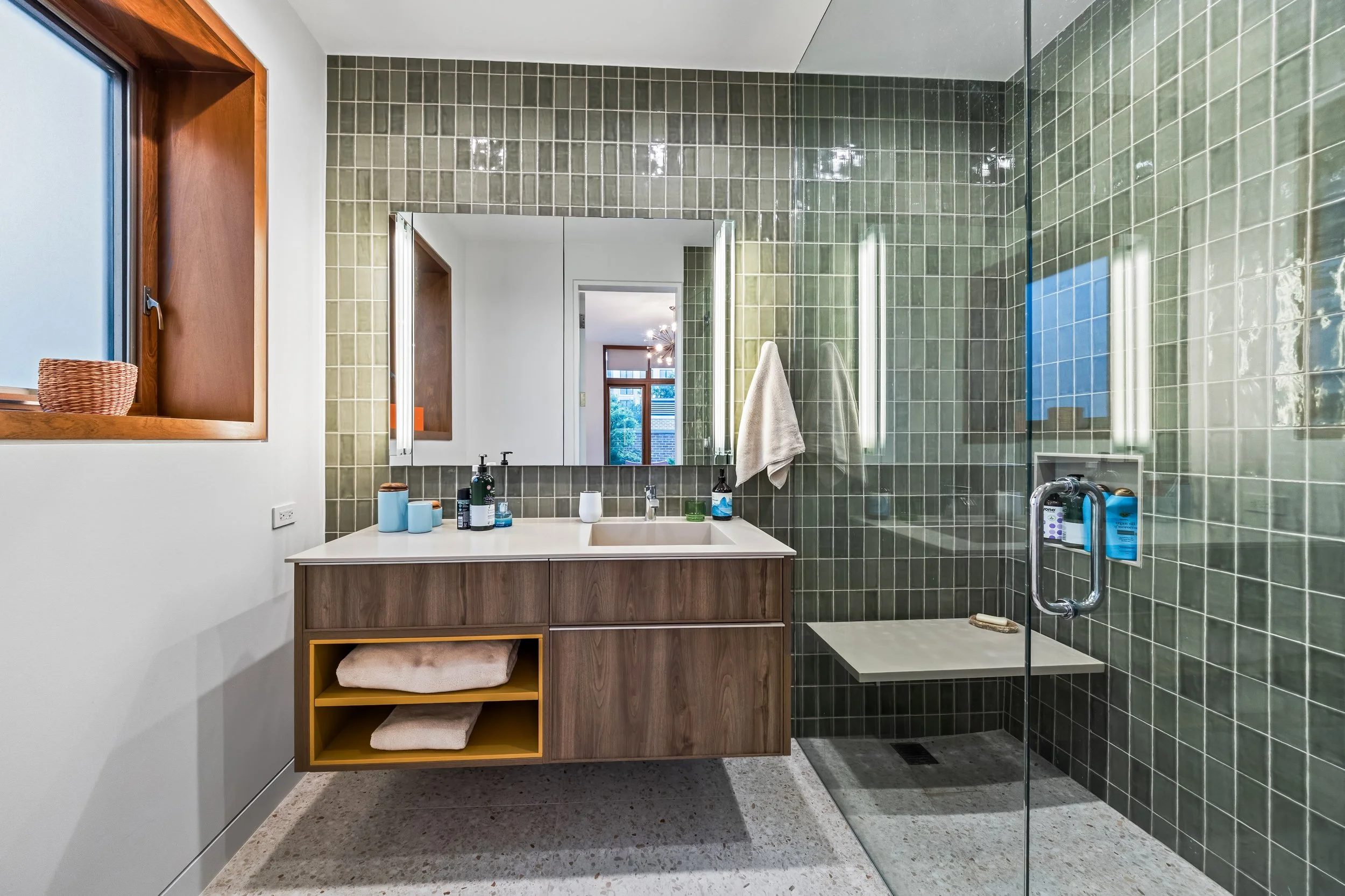 Modern bathroom remodel with custom green subway tile installation and built-in vanity seating in Bucktown Chicago.