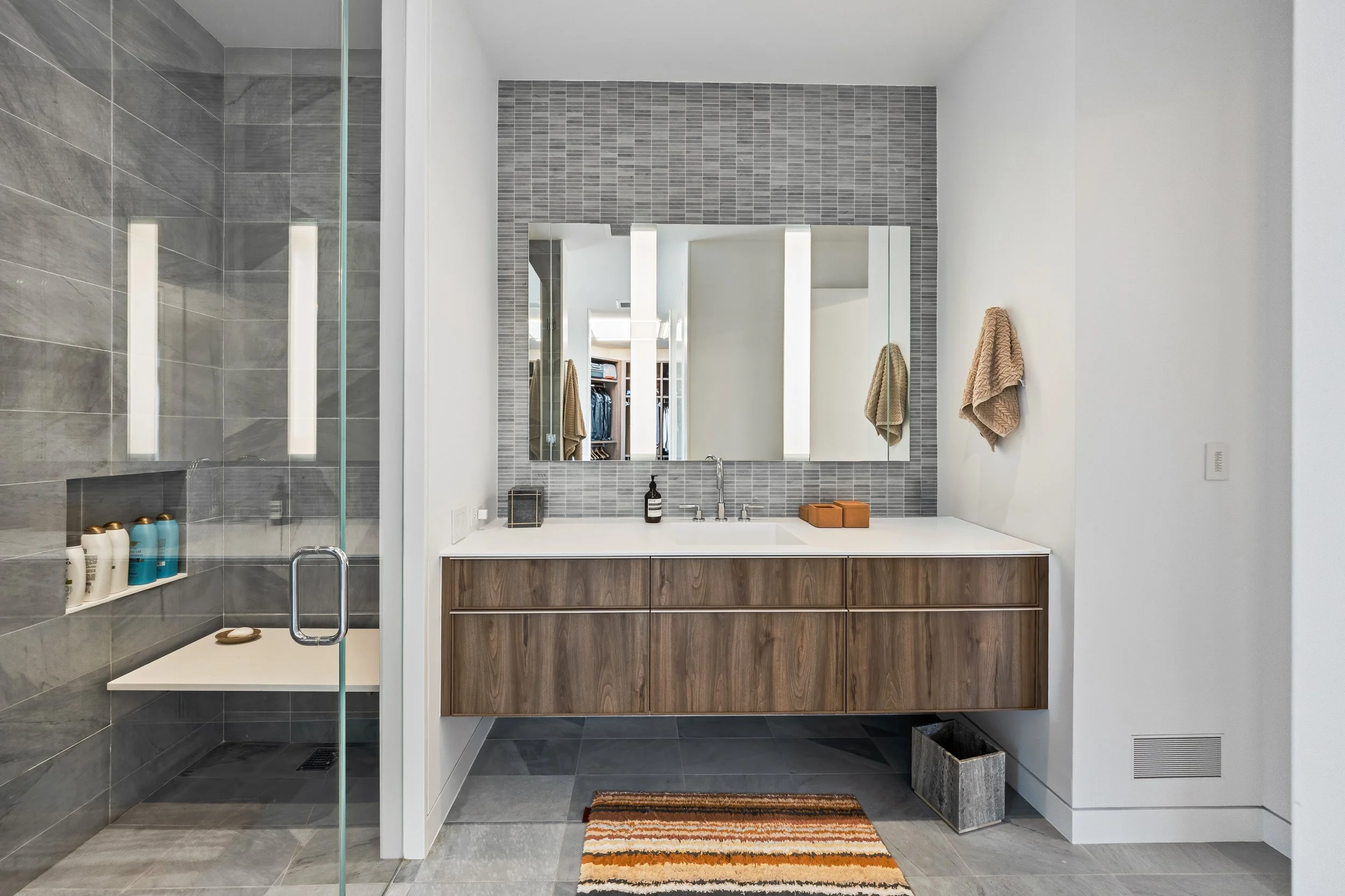 Custom floating wood vanity and grey textured tile shower remodel in North Center Chicago residence.