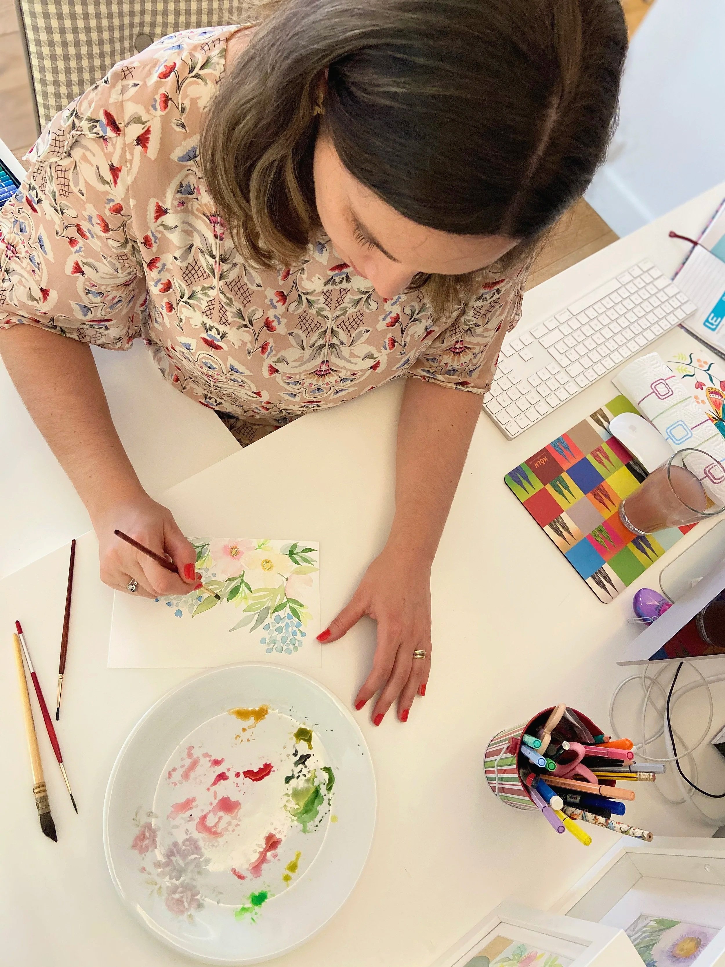 Illustratrice et designer textile travaillant sur une peinture florale à l’aquarelle dans son studio créatif, source d’inspiration pour la création de motifs de surface.