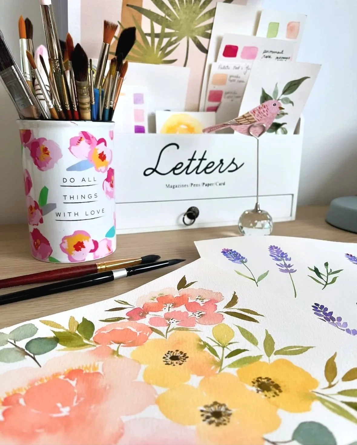 Espace de travail du studio Fleur de Liza avec pinceaux, illustrations botaniques à l’aquarelle et échantillons de couleurs.