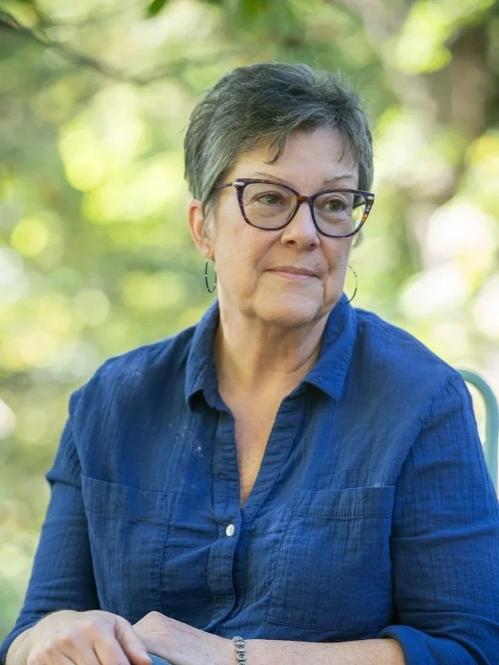 Portrait of author, illustrator, and fine artist Tammy Tatum seated outdoors, wearing a blue shirt and looking thoughtfully off camera.