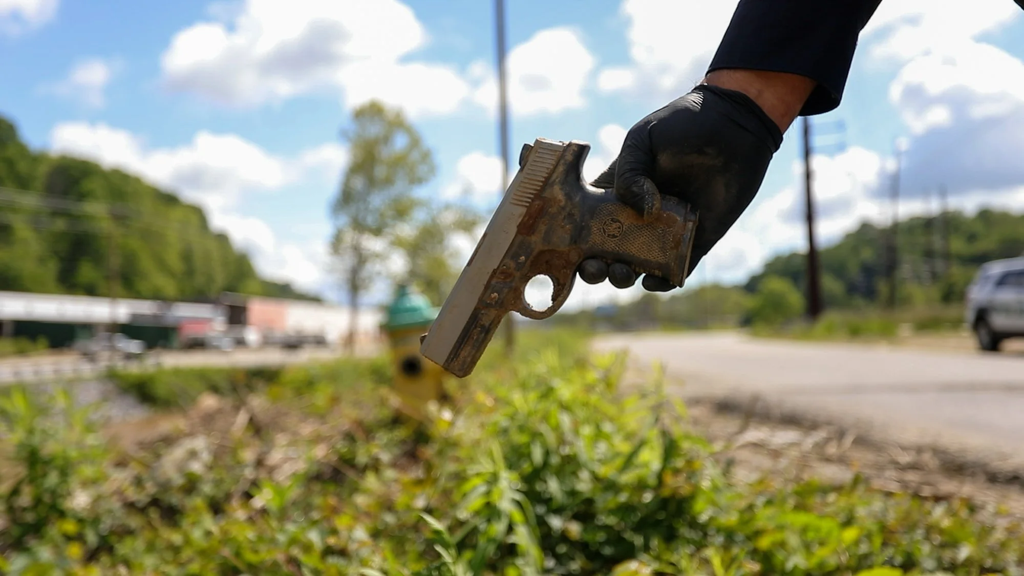 An Asheville policeman holds a handgun that was uncovered in the mud along the French Broad by Wynn Arellano. A small glimpse into the plethora of items the team finds during their work day.