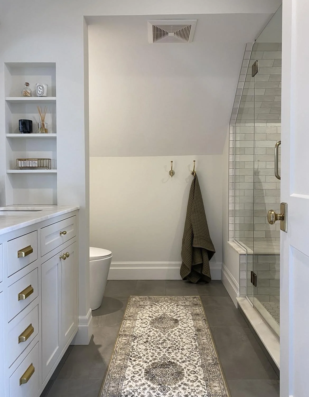 Modern bathroom with a white vanity, decorative rug, walk-in shower, and hanging towel.