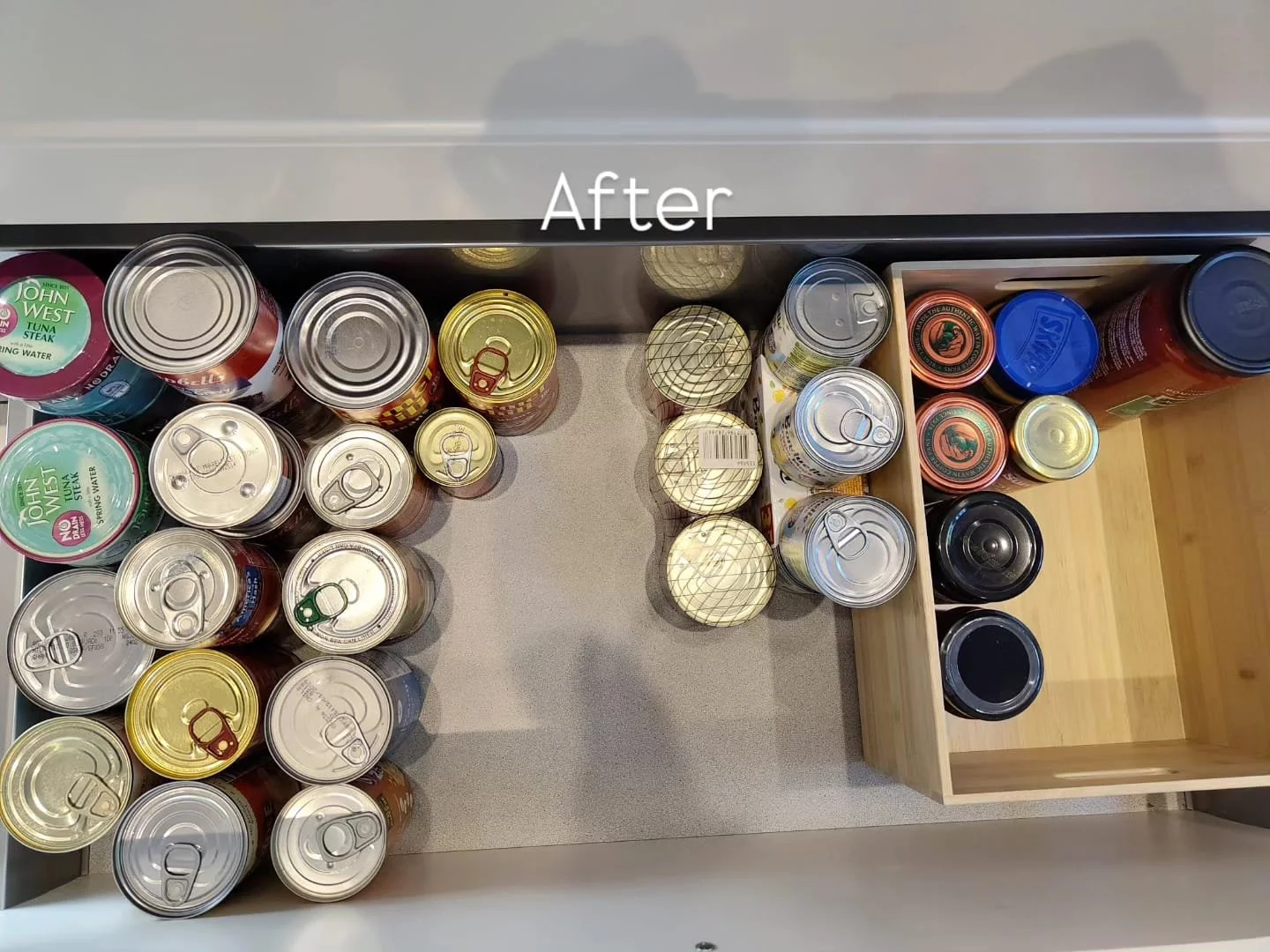 Organized canned foods in a kitchen drawer, labeled 'After', with some canned goods in a wooden compartment and some in the main drawer.