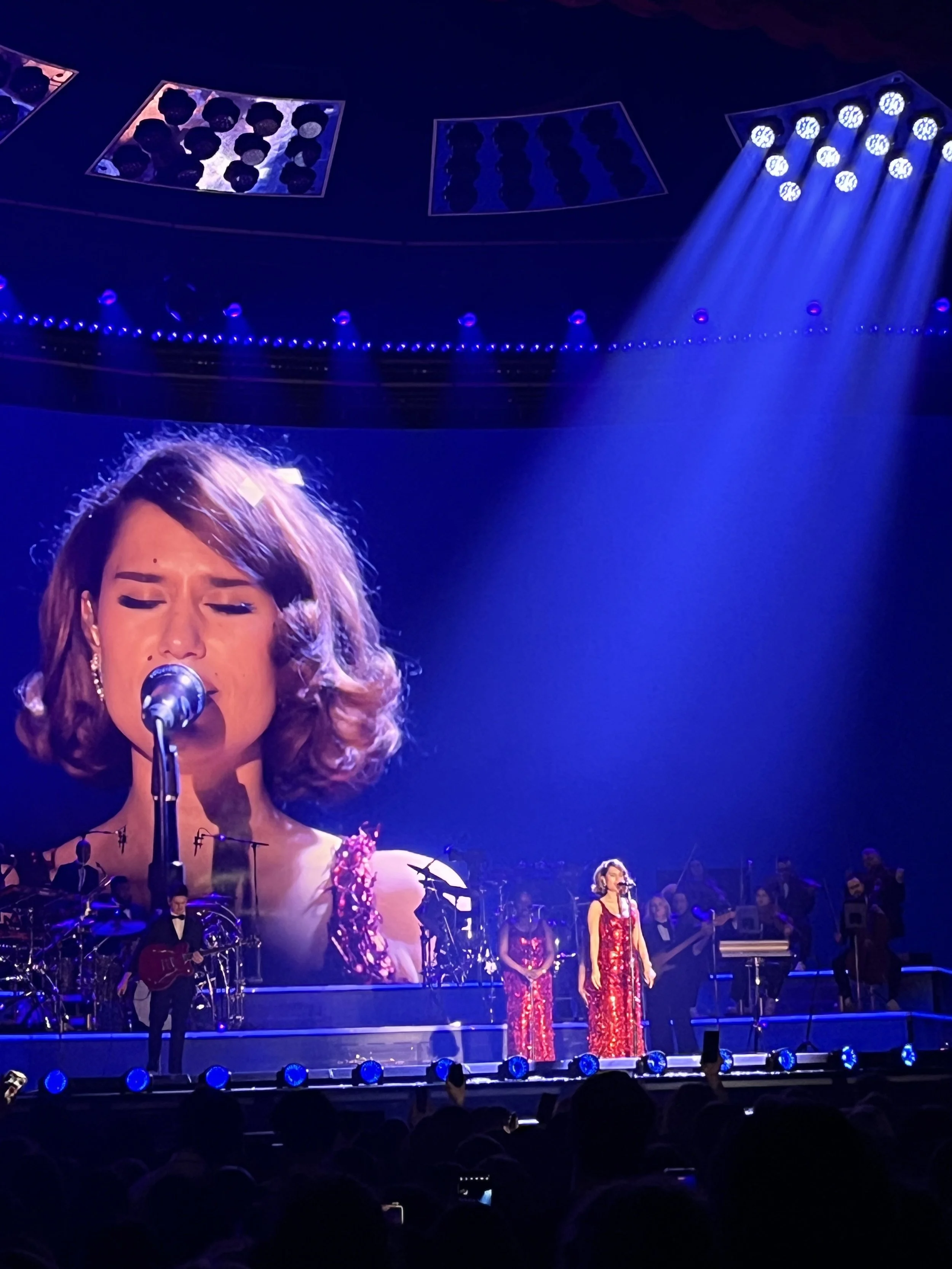 Raye on stage in her sparkling red dress backed by her large band.