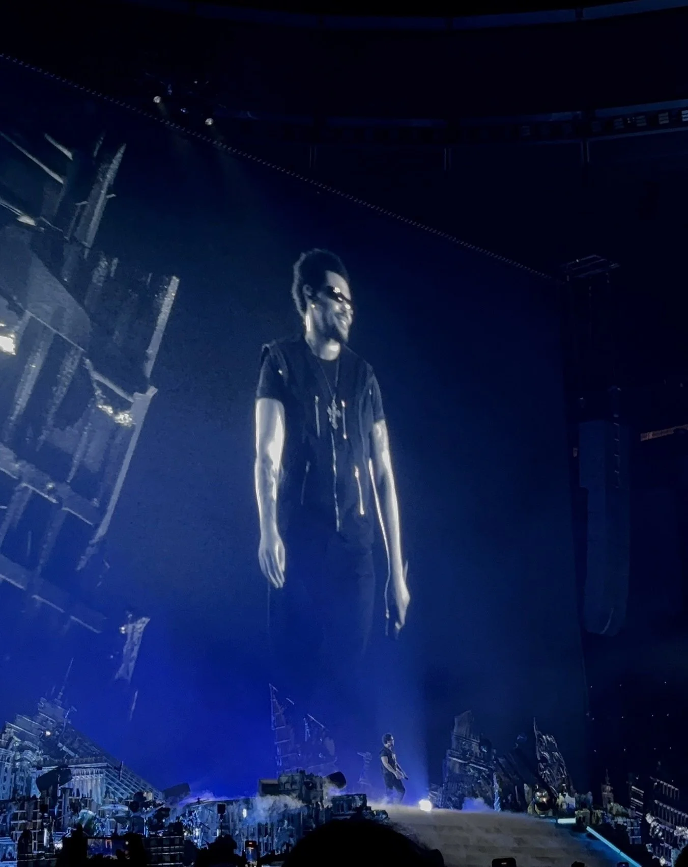 The Weeknd performing live in Madrid seen on stage and the big screen wearing sunglasses.