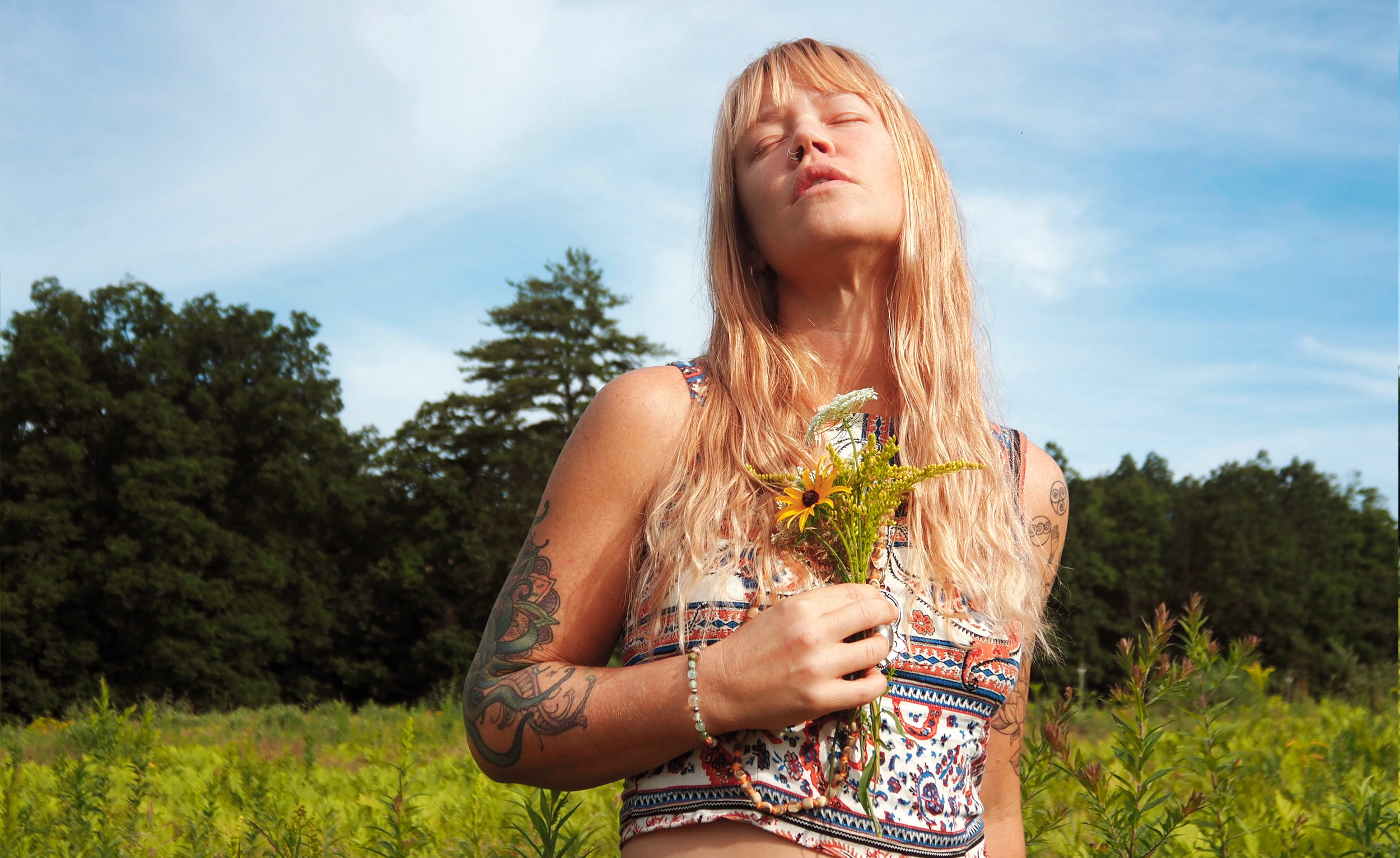 A woman with long blonde hair and tattoos. Intuitive feminine leadership and authentic brand expression for women rebuilding wellness and service-based businesses