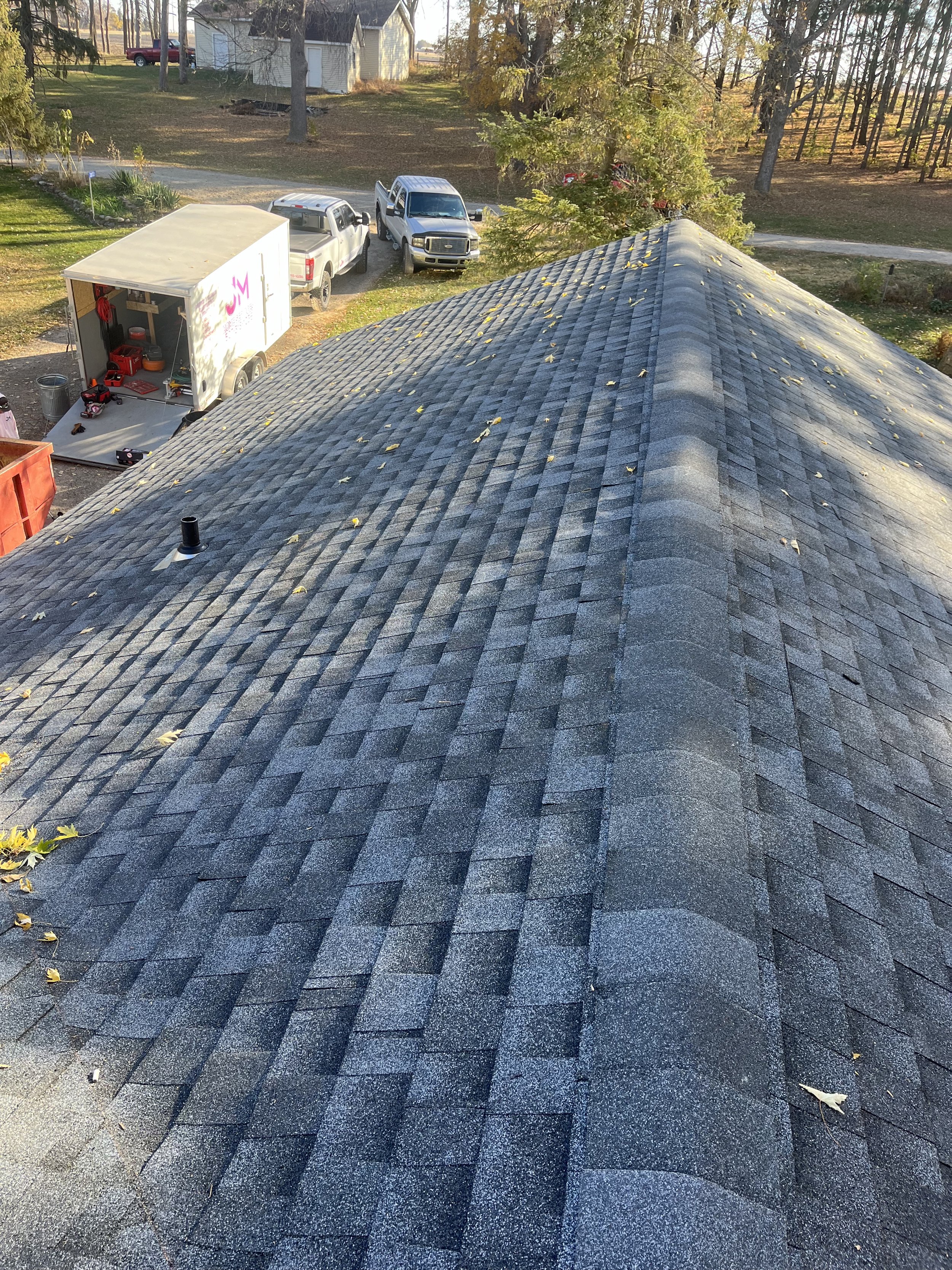 asphalt shingle roof with parked vehicles and trees