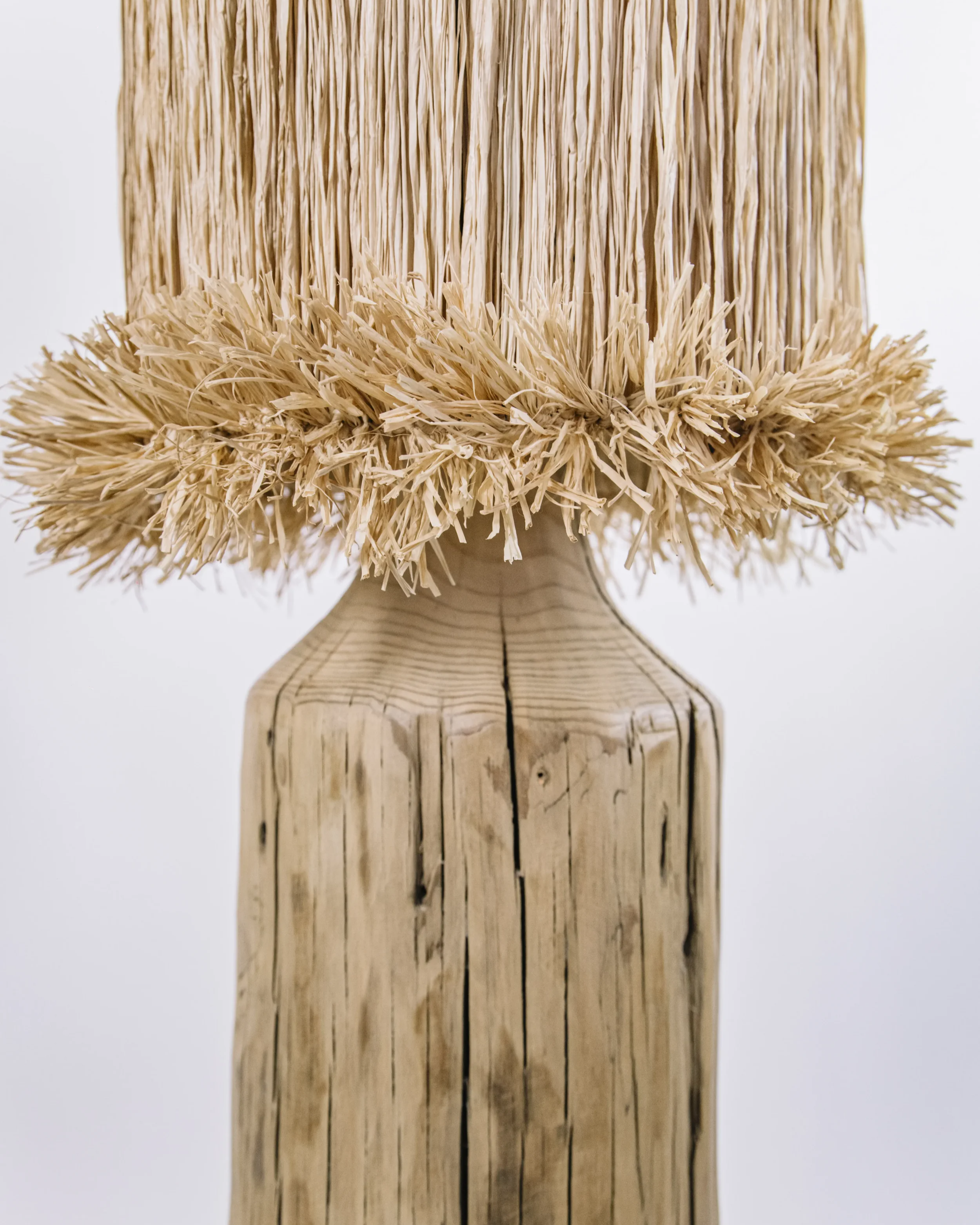 Detalle de lampara artesanal con fibras naturales y madera maciza, textura organica y luz calida