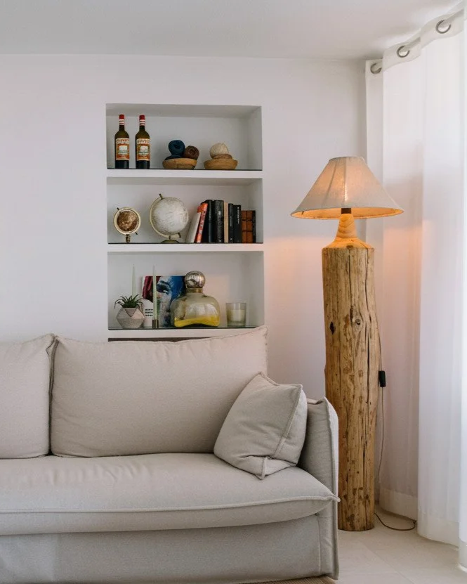 Lámpara de pie de troncos de madera recuperada con pantalla de lino en un salón de estilo mediterráneo