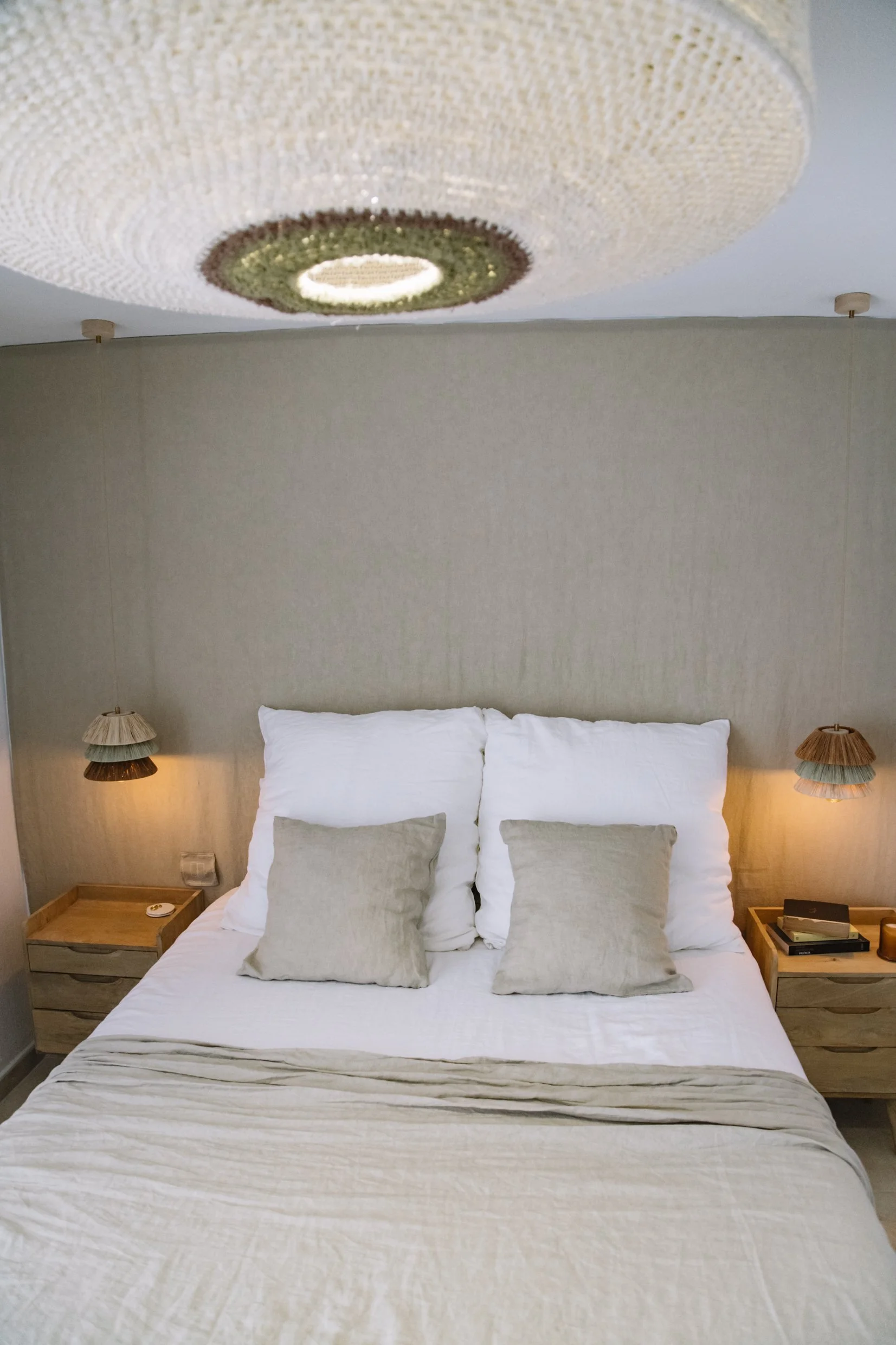 Dormitorio con iluminación cálida y suave mediante lámparas artesanales de pared, creando un ambiente sereno y acogedor.