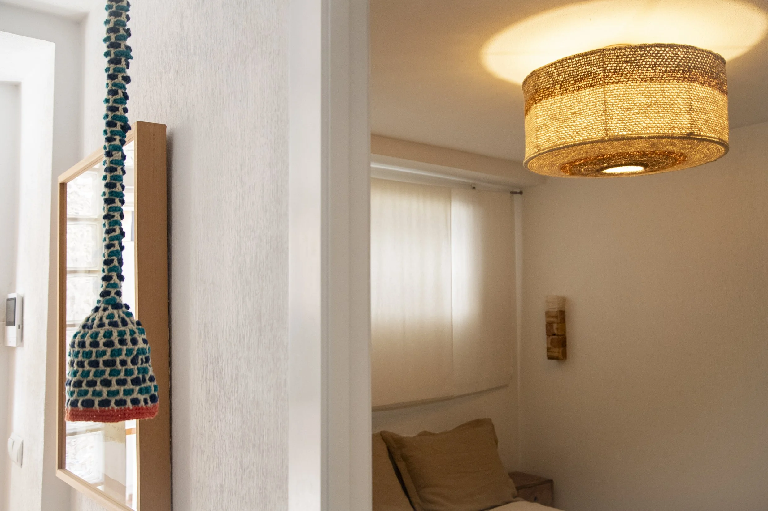 Detalle de lámpara artesanal de fibras naturales que crea una luz cálida y envolvente en un espacio interior.