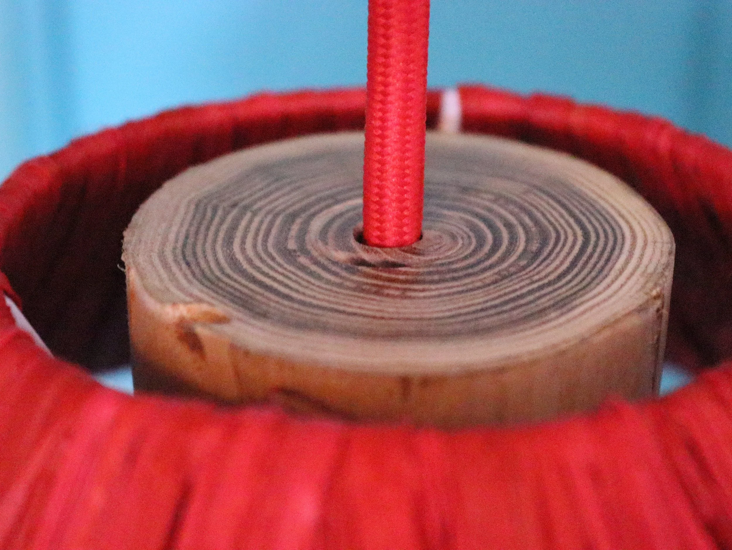 Estructura de madera y cable rojo en lámpara TRINA de rafia, diseño artesanal de dosana