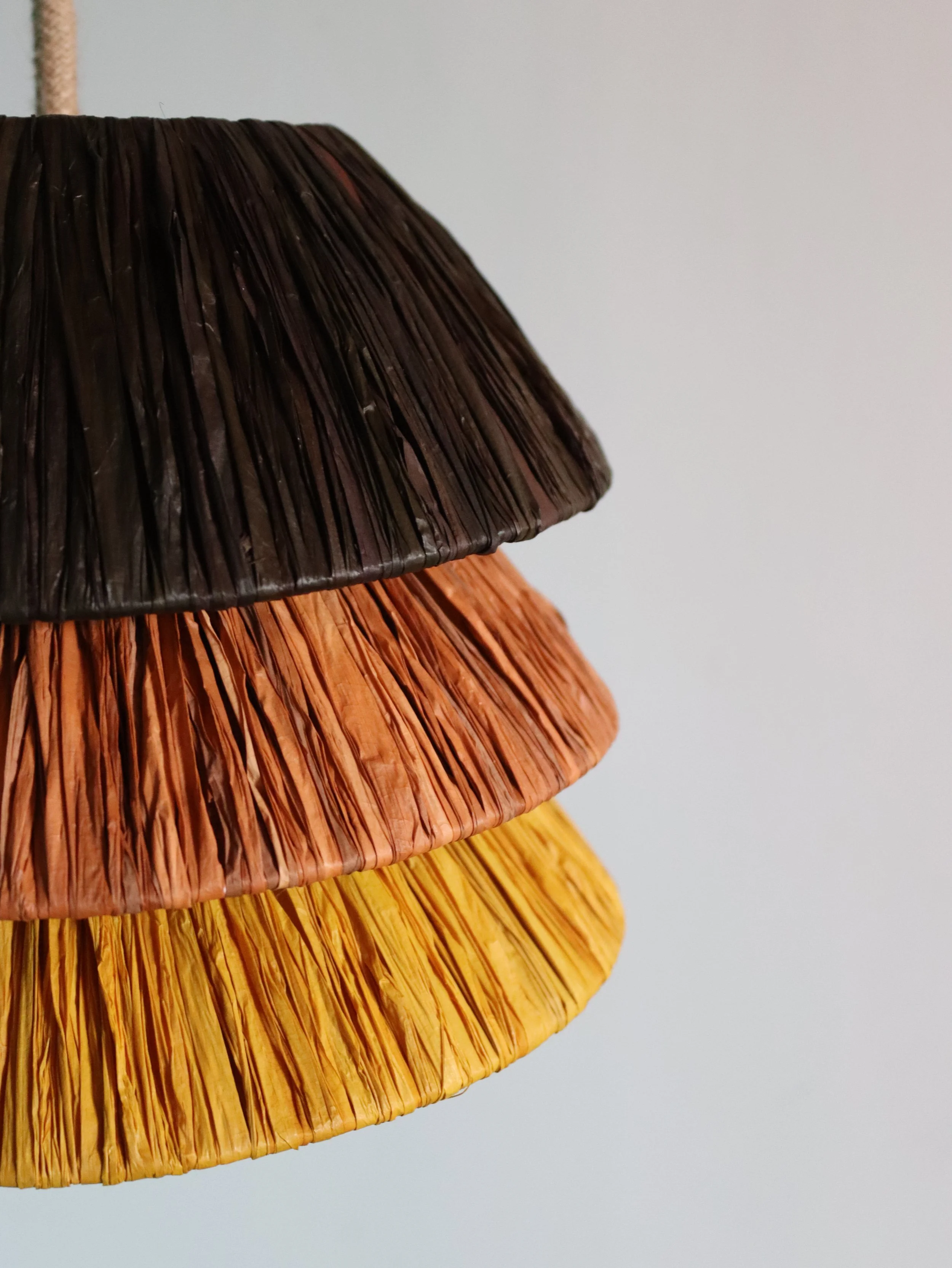 Detalle de lámpara TRINA de rafia artesanal en tonos cálidos, hecha a mano por dosana