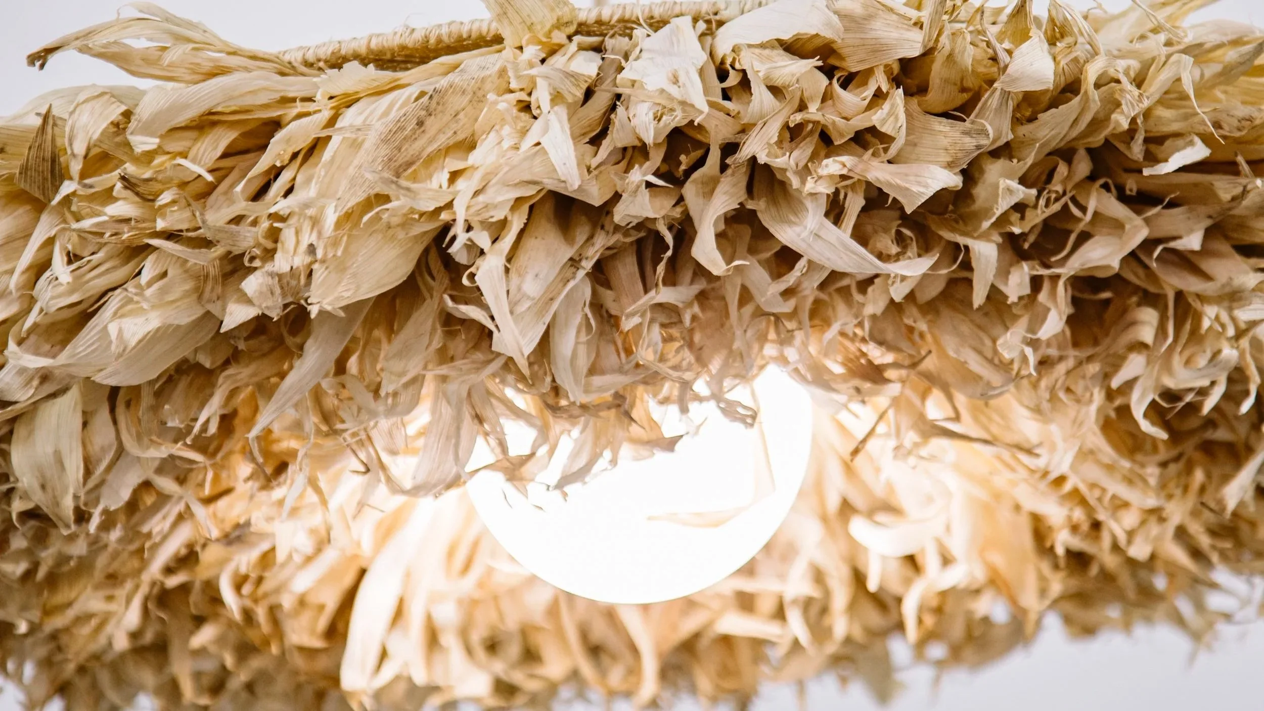 Detalle de hojas de maiz natural en lampara artesanal con luz calida filtrada y textura organica