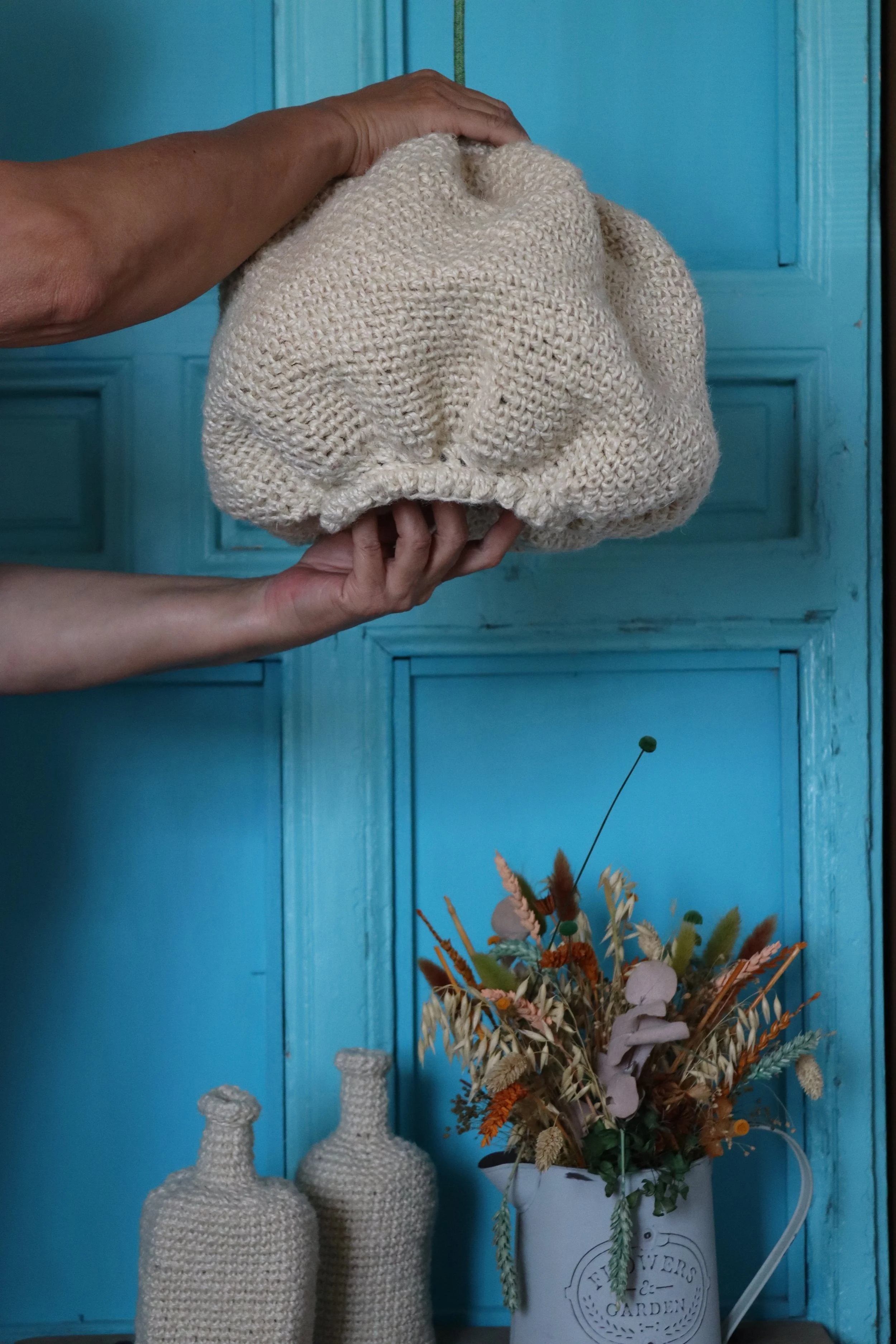 Manos sosteniendo una lámpara artesanal tejida a mano durante el proceso de creación.