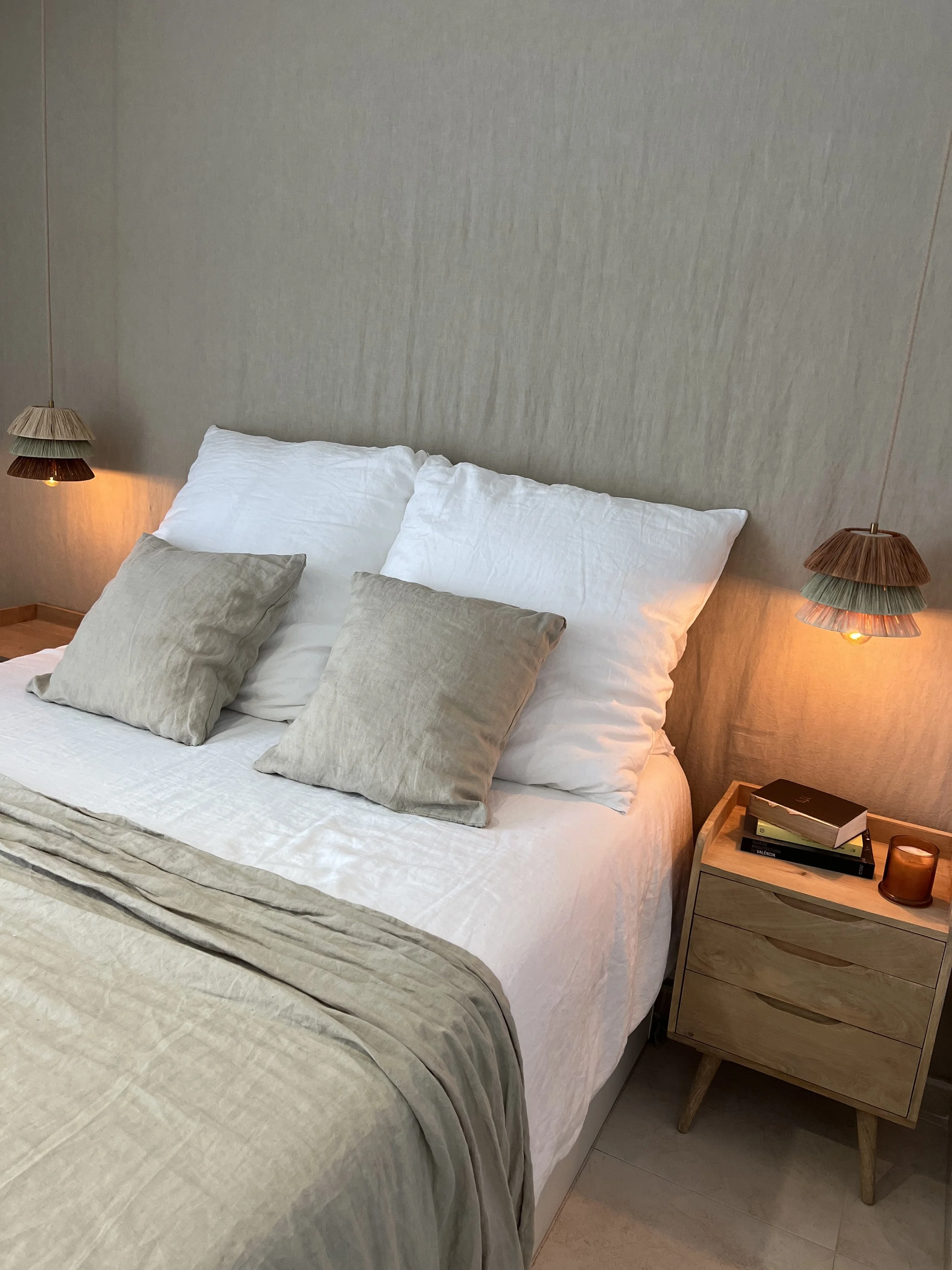 Dormitorio de inspiración mediterránea iluminado con una lámpara artesanal.