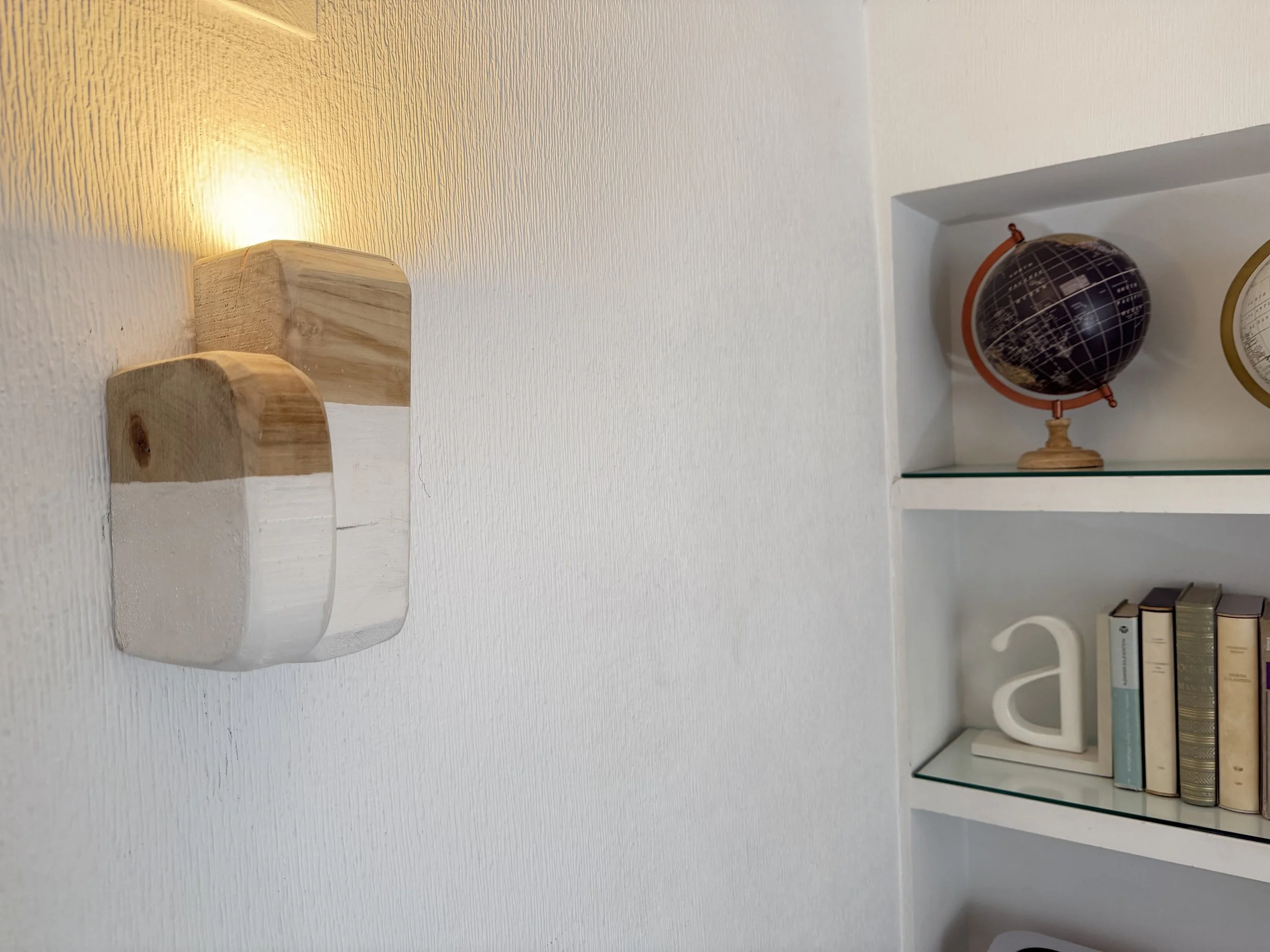 Aplique de pared Savira en madera maciza con luz indirecta, integrado en una zona de paso de un proyecto de interiorismo.