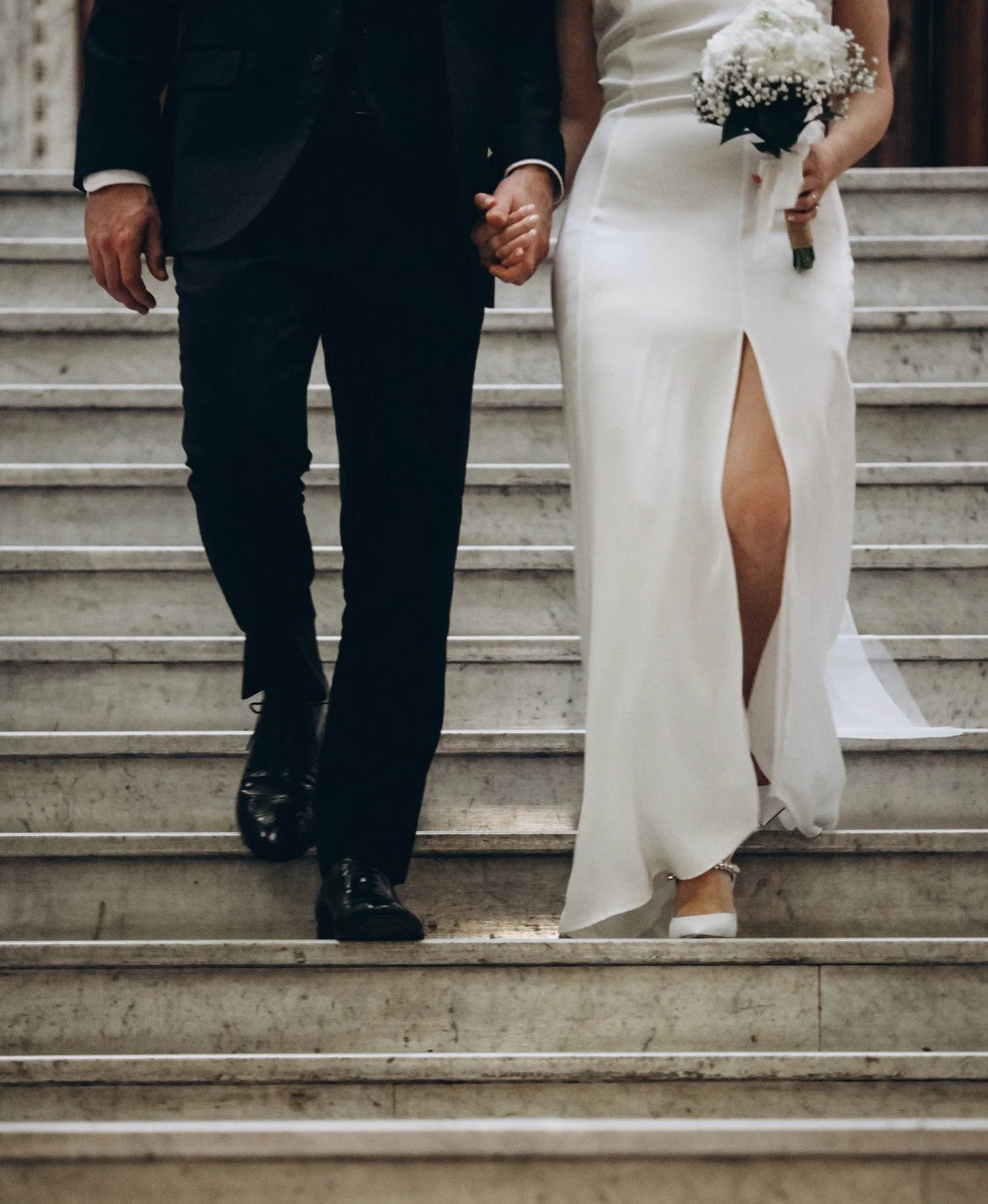 A bride and groom holding hands, exchanging a tender moment during their wedding ceremony in Greece. Surrounded by breathtaking scenery, their connection radiates love and happiness, capturing the intimate and emotional essence of a timeless destinat