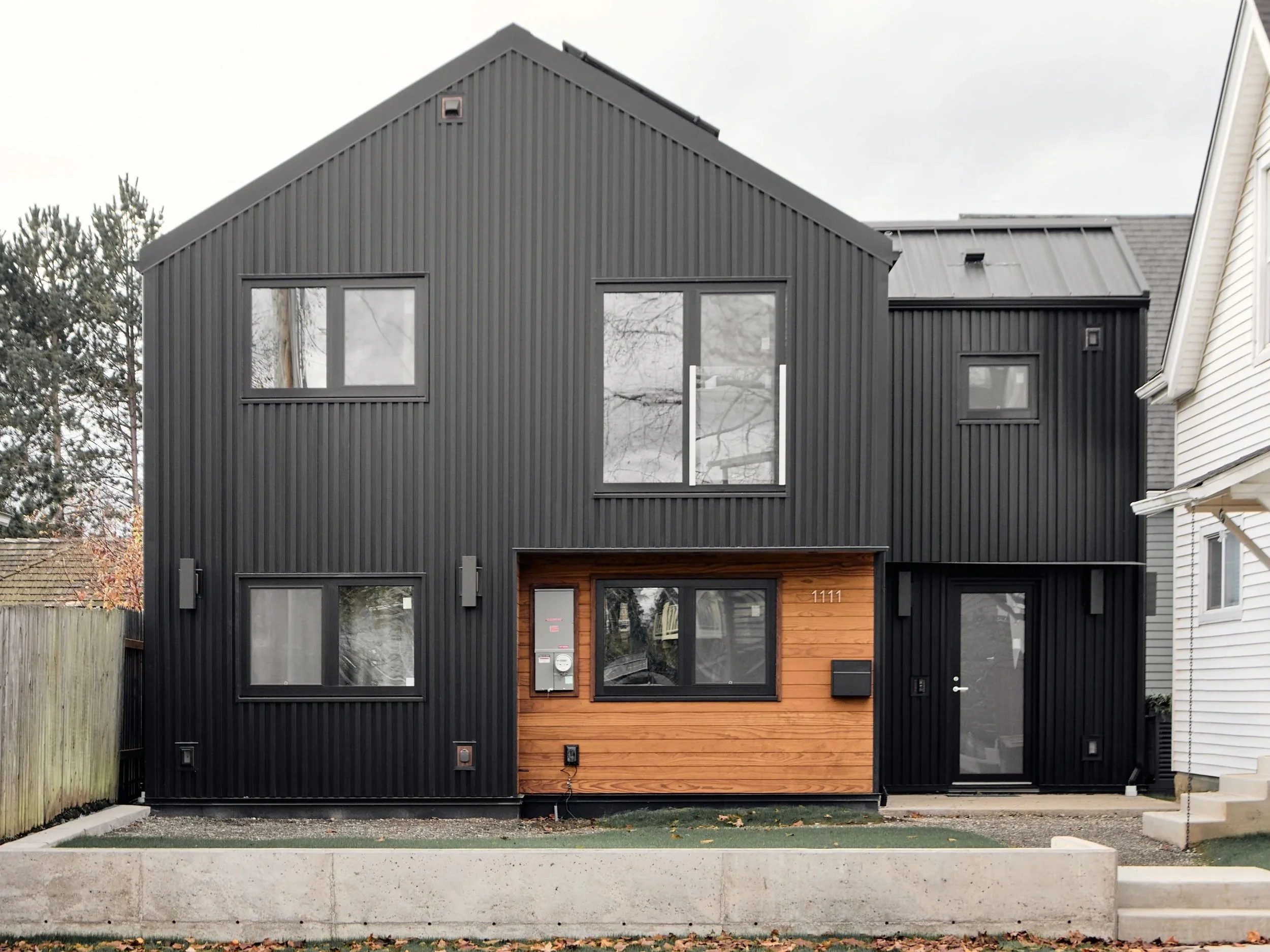Custom DADU exterior by Fox Lake Builders, Bellingham WA — black standing-seam metal cladding, wood entry canopy.