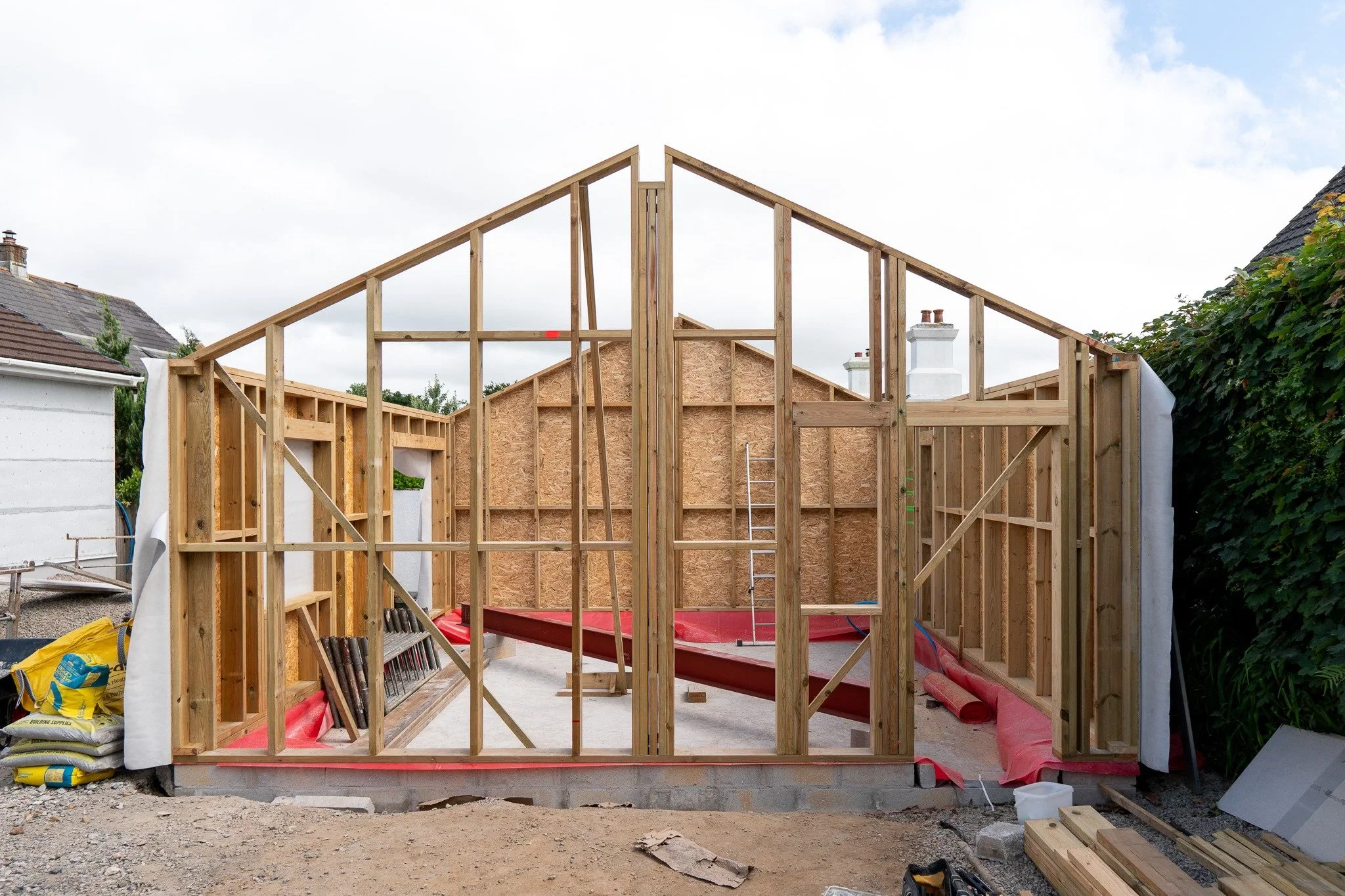 Home construction site with wooden framing for walls and roof.