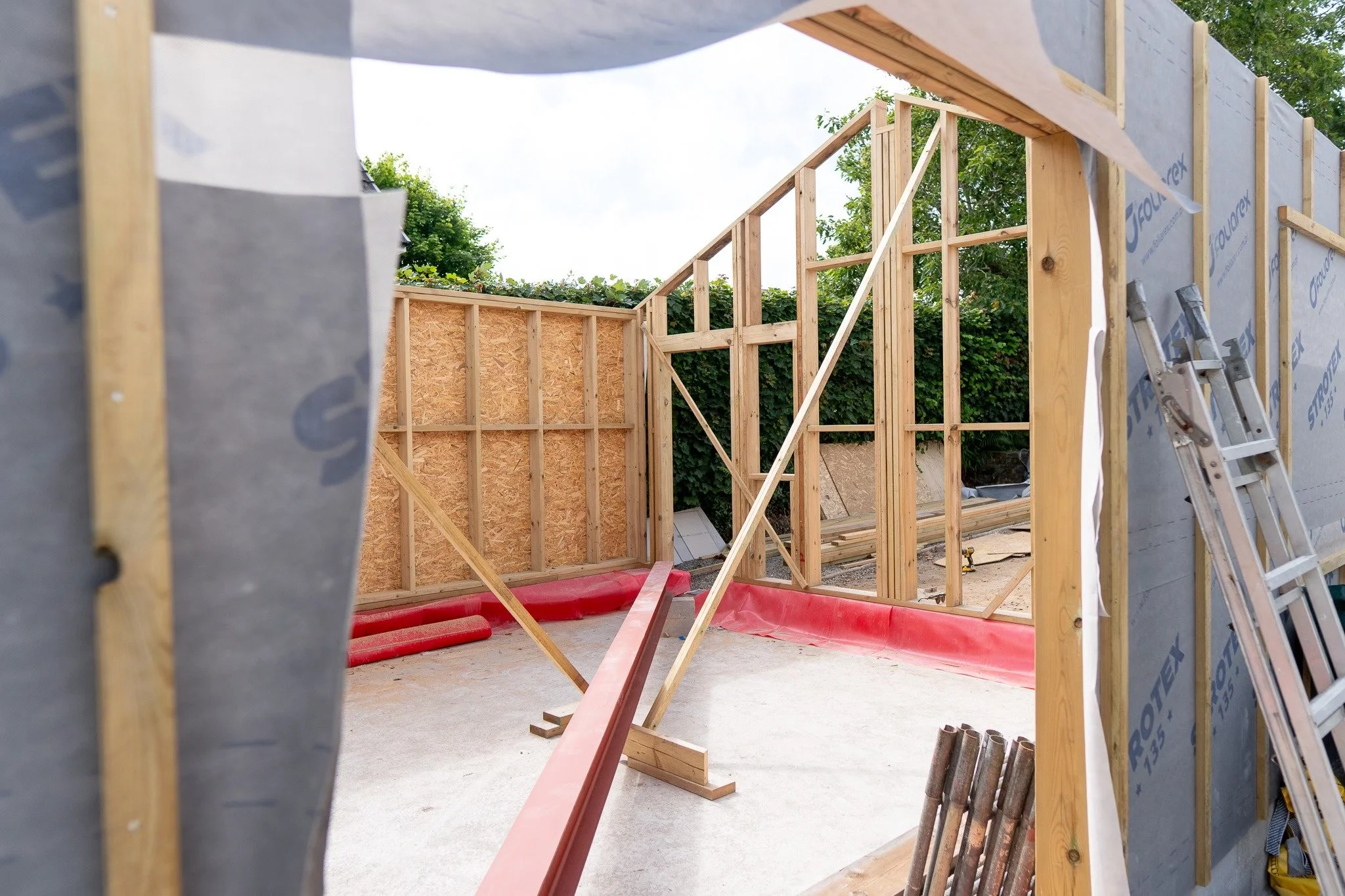 Construction site with wooden framing, ladder, and construction materials for building a house or structure.
