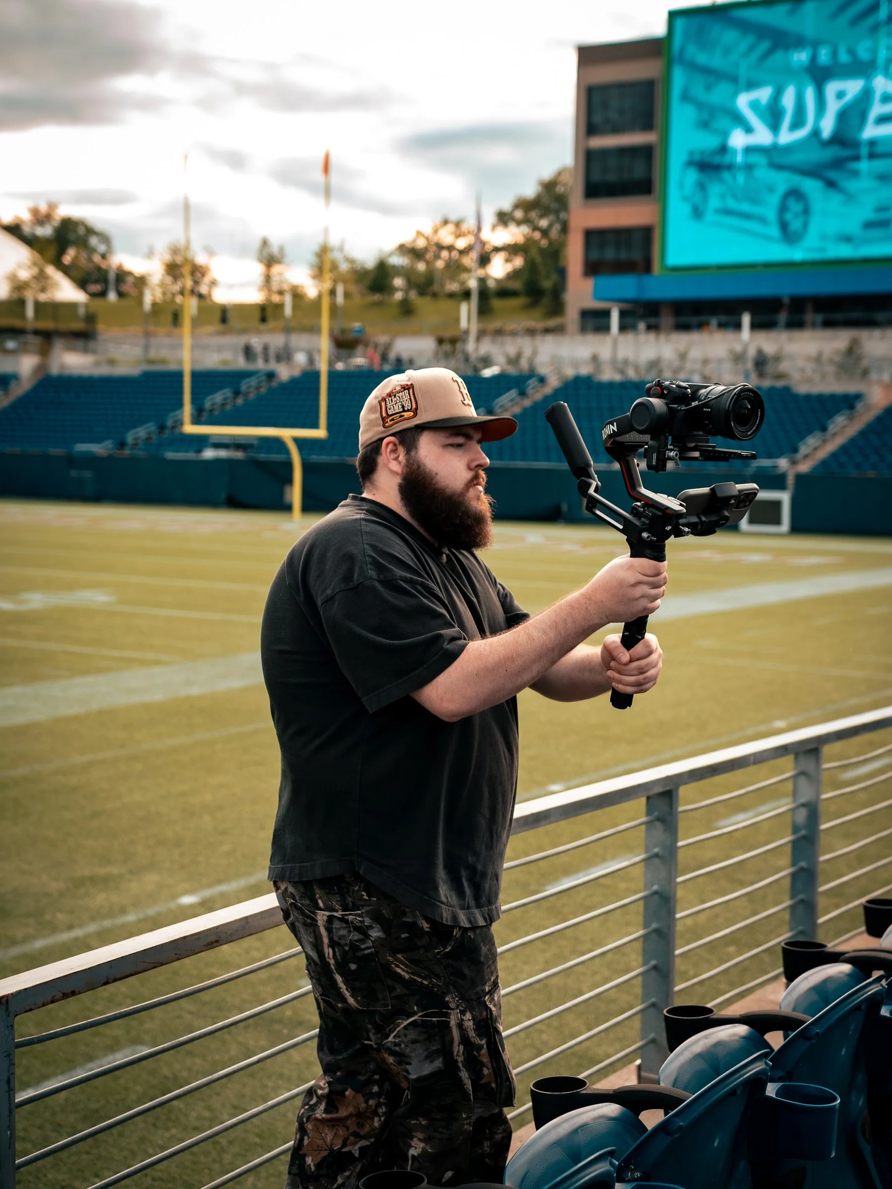 Treven Warner filming with a camera and gimbal in Tom Benson Hall of Fame Stadium.