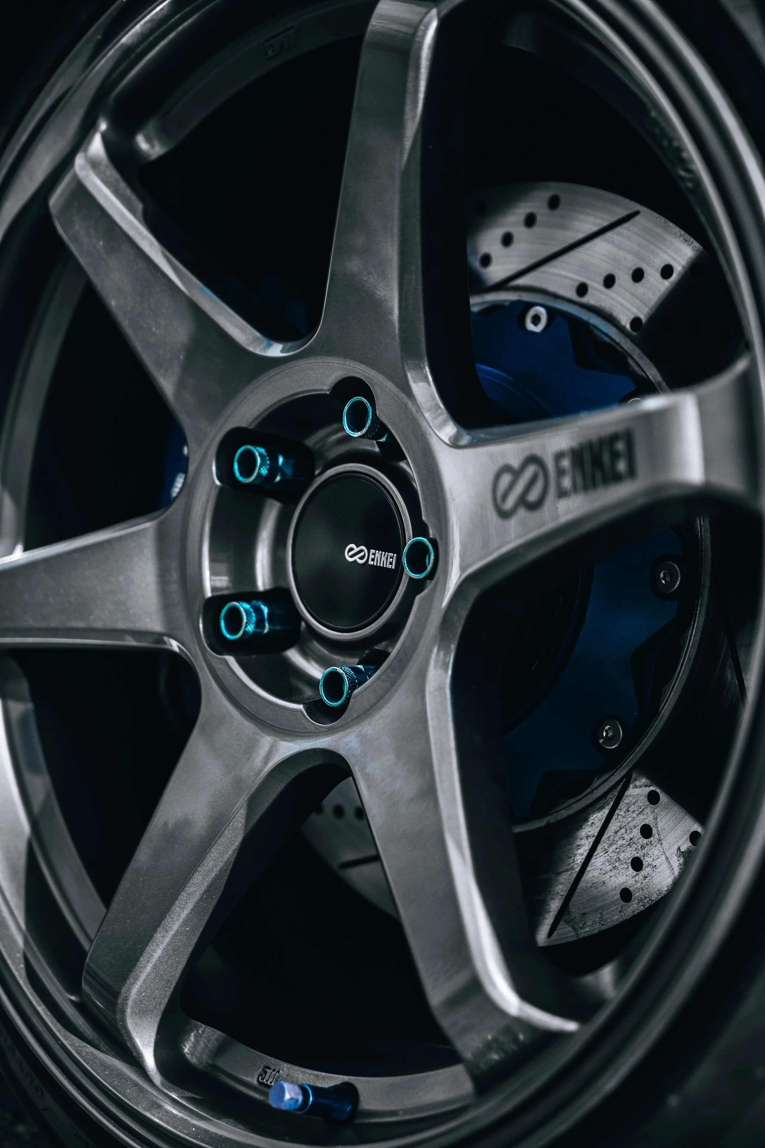 Close-up of Enkei alloy wheel and drilled brake rotor on a performance car.