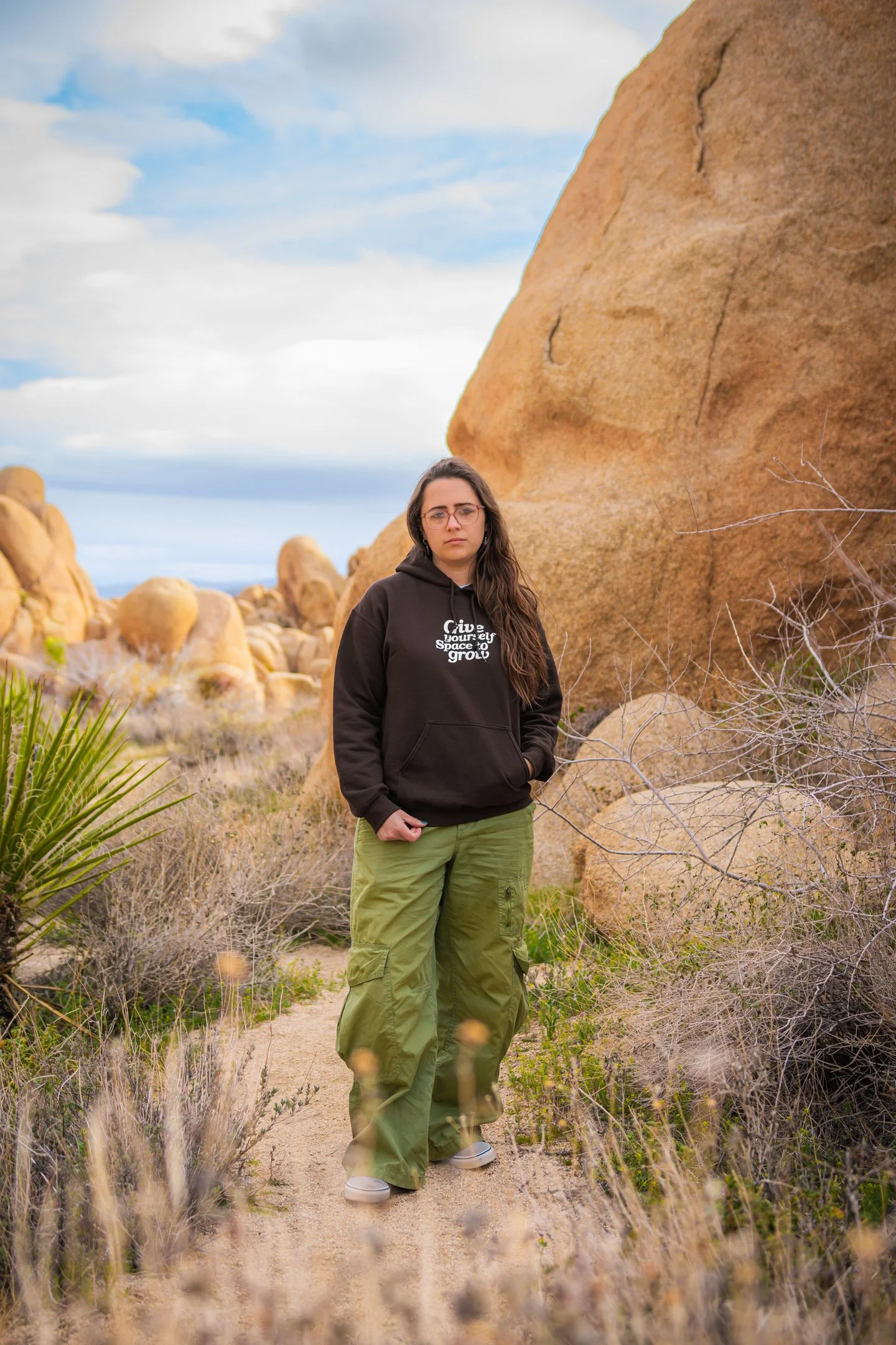 Portrait for Sneaker Queens Customs’ “Give Yourself Space to Grow” merch drop, shot in Joshua Tree National Park among desert rocks and plants.