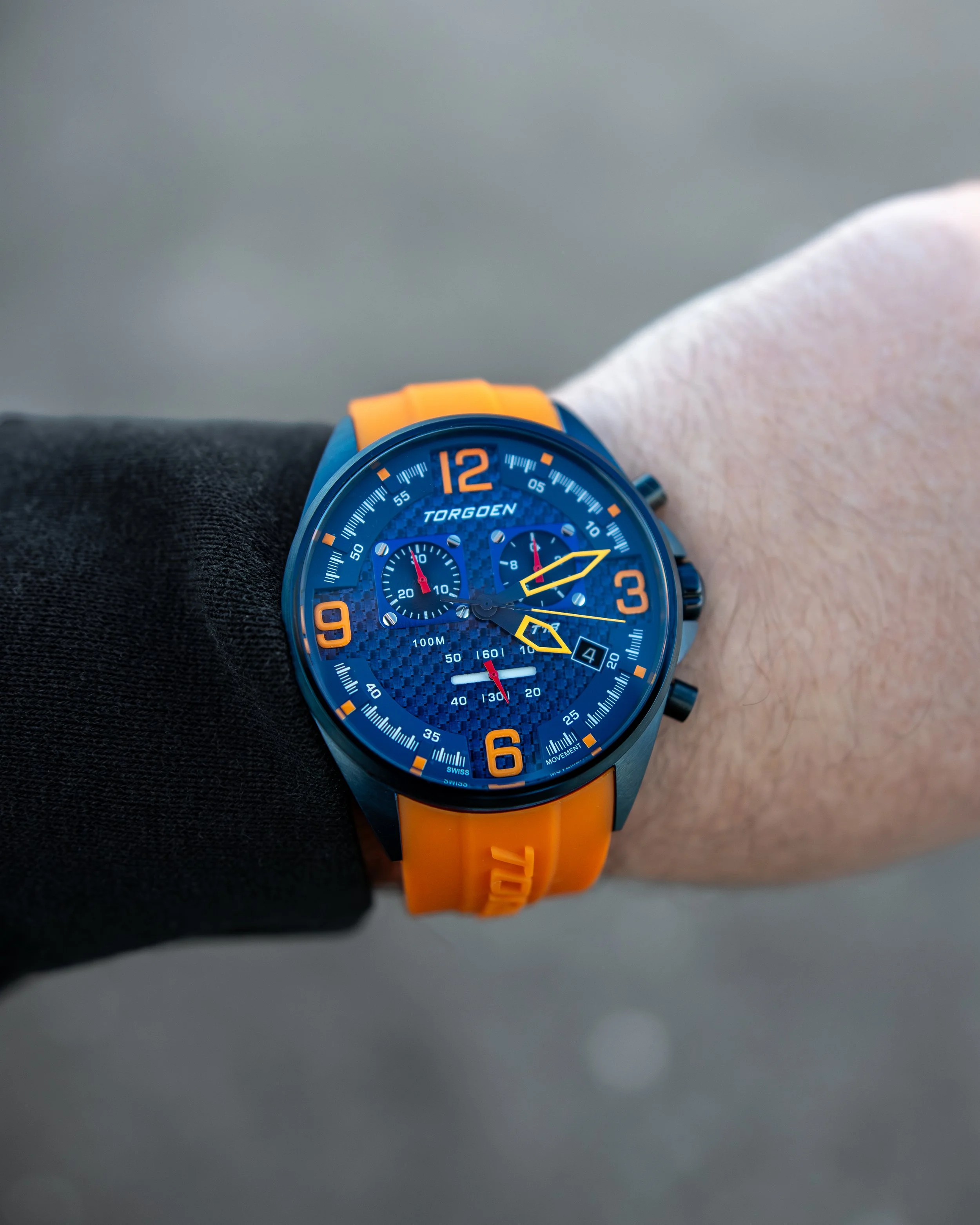 Torgoen T18 watch with blue dial and orange strap on wrist, lifestyle product photography.