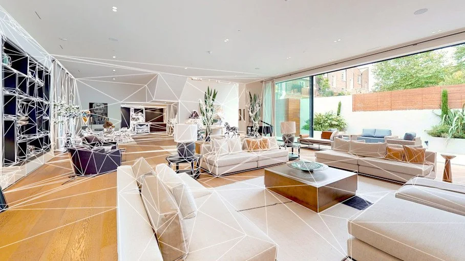 Modern living room with large windows, white sofas, coffee tables, and indoor plants.