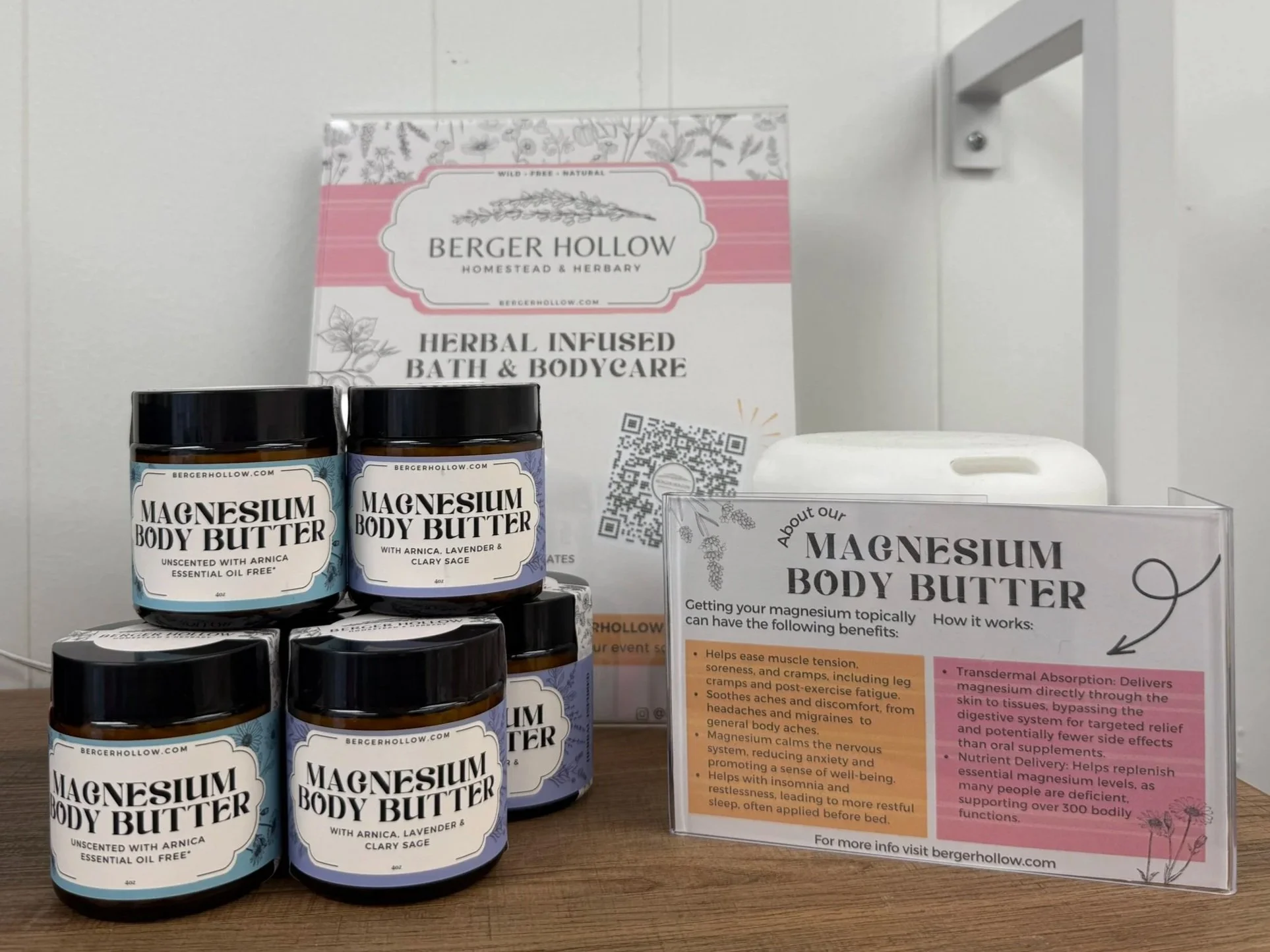 Display of gourmet magnesium body butter jars, herbal bath and bodycare informational sign, and marketing stand with product benefits